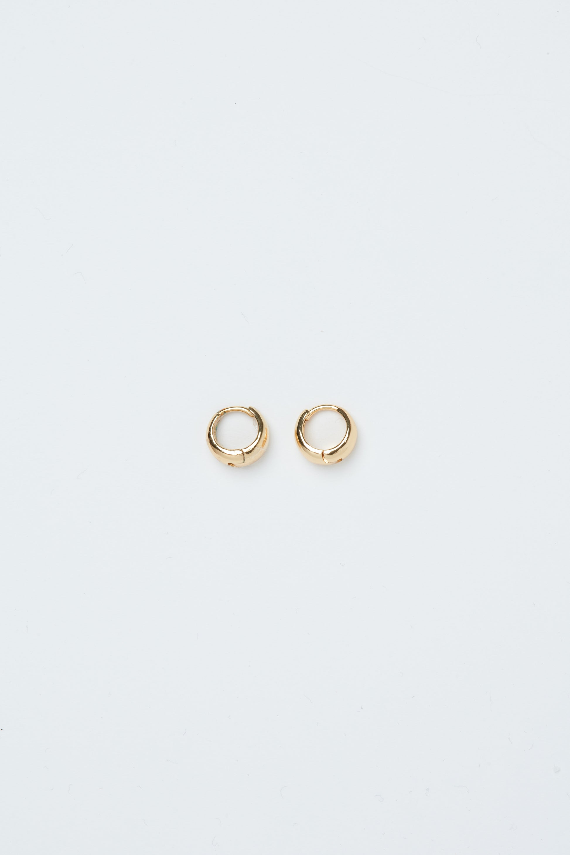 Pair of gold hoop earrings on a light gray background