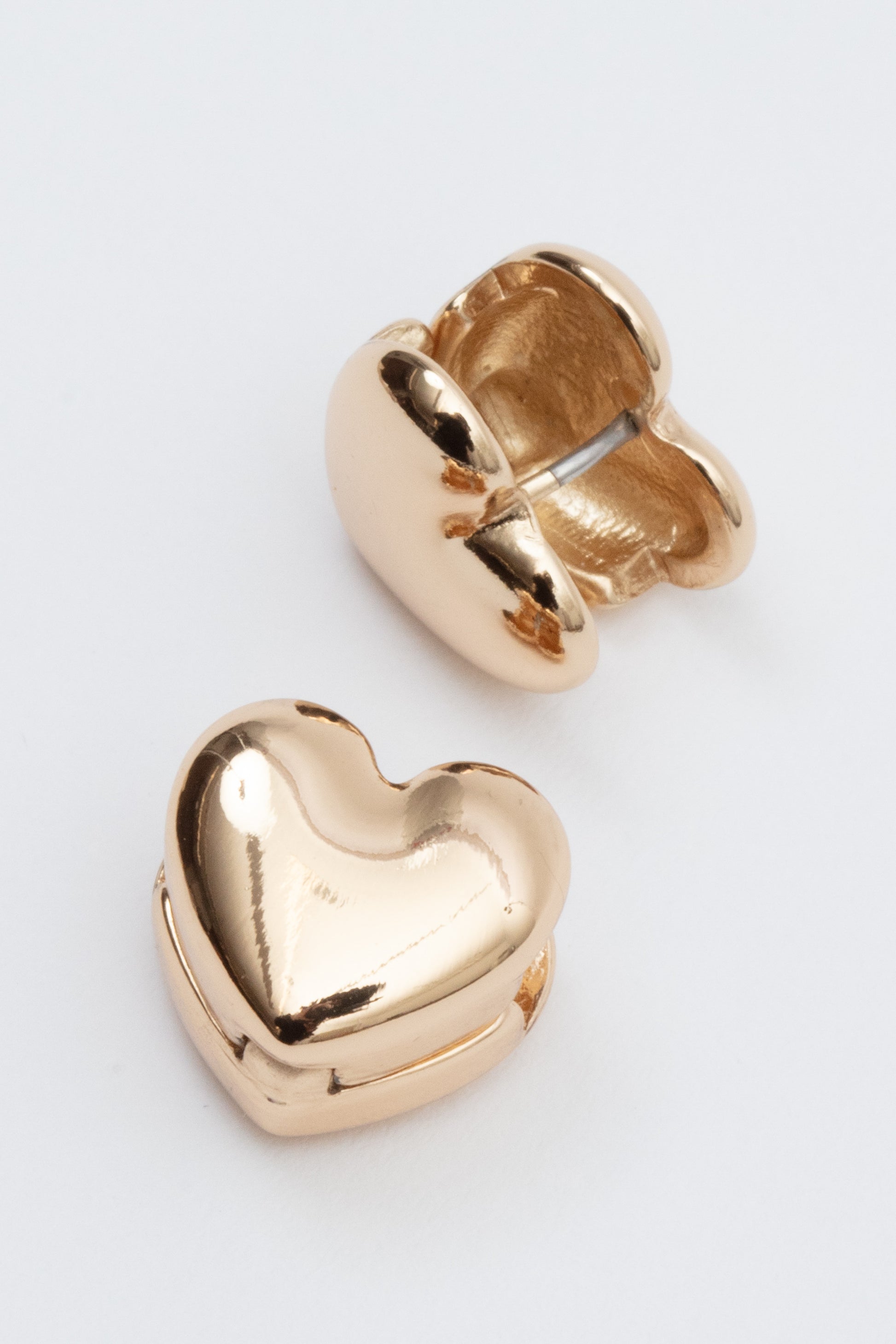 Gold heart-shaped earrings on a light gray background