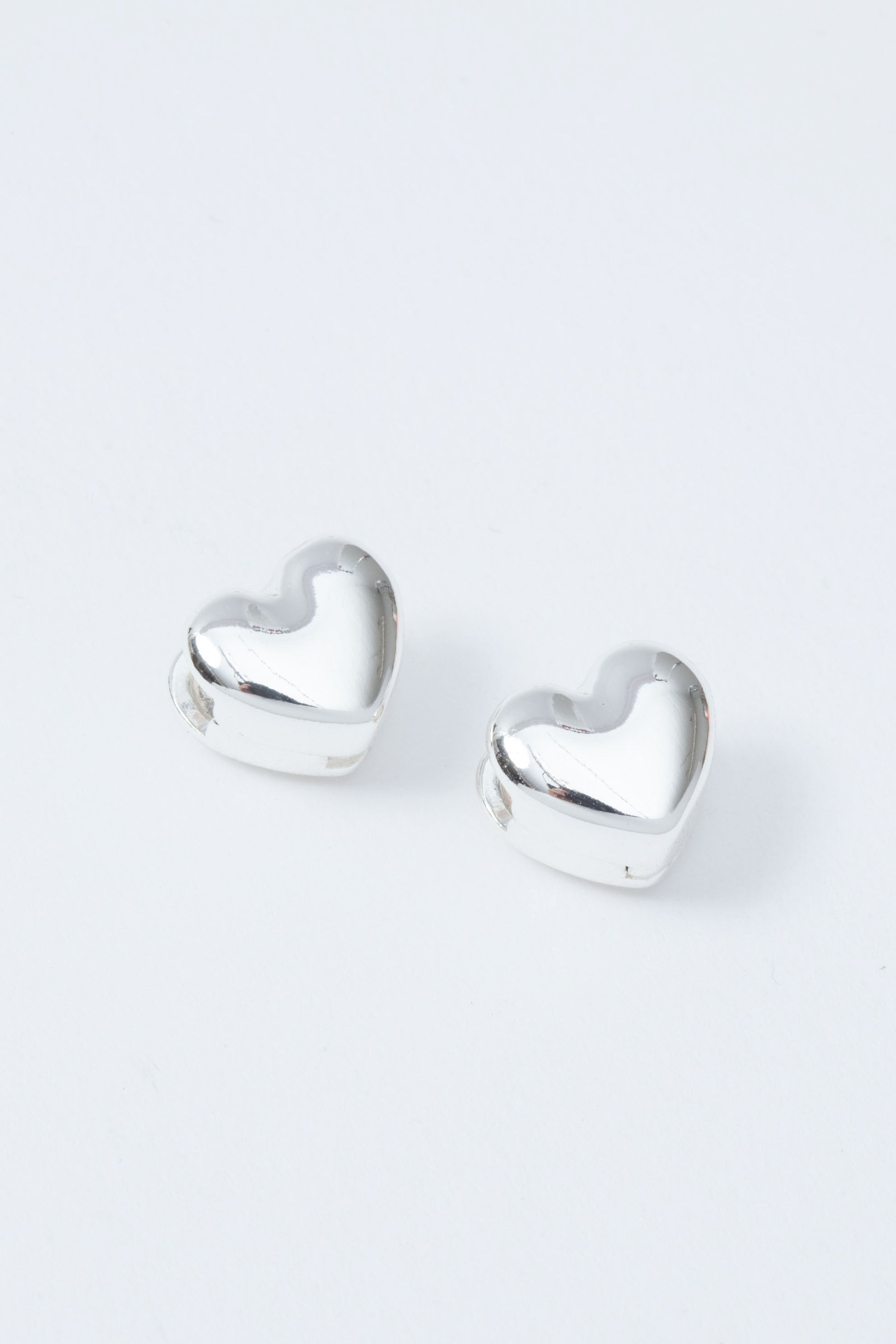 Heart-shaped silver earrings on a white background