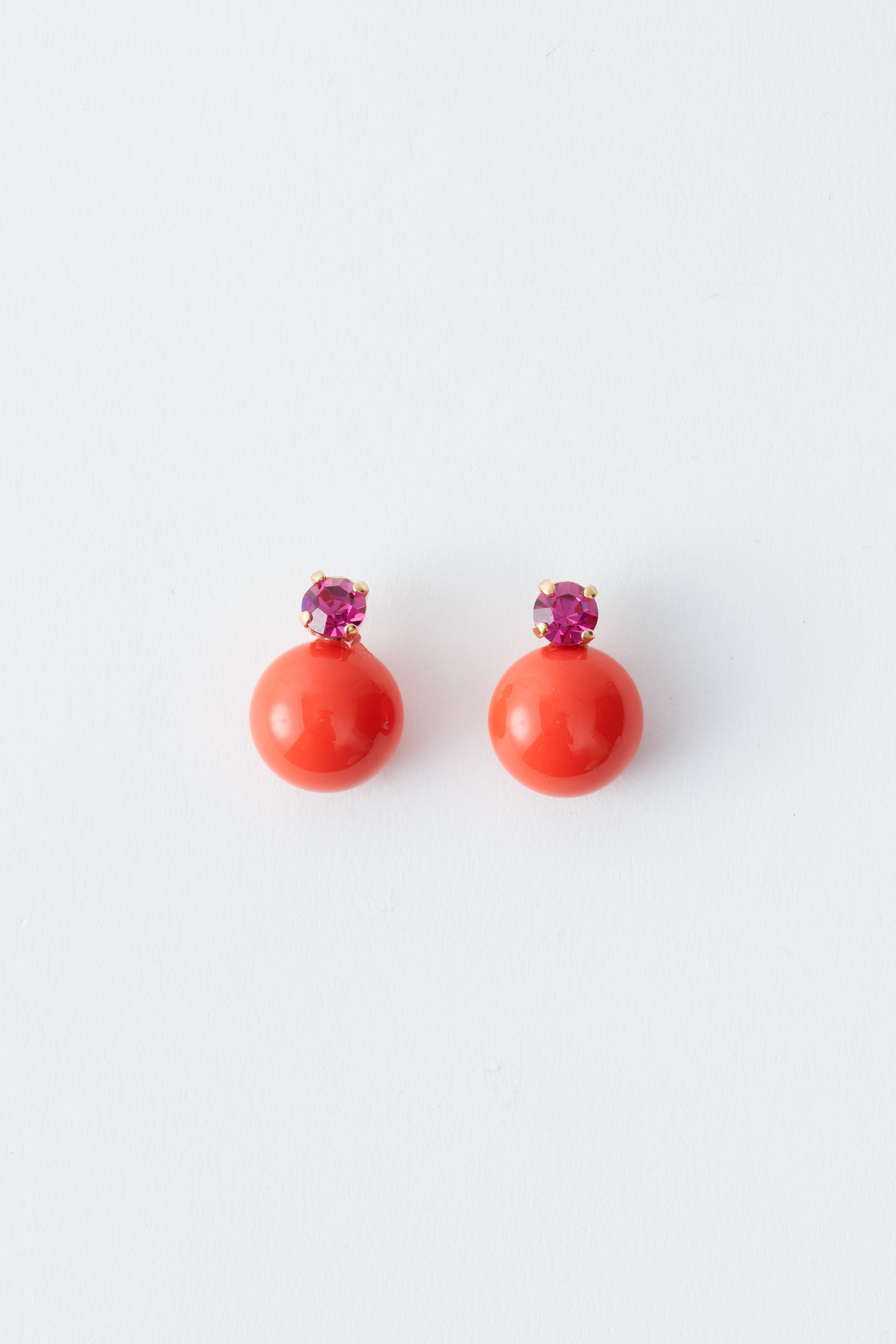 Pair of coral earrings with purple tops on a white background