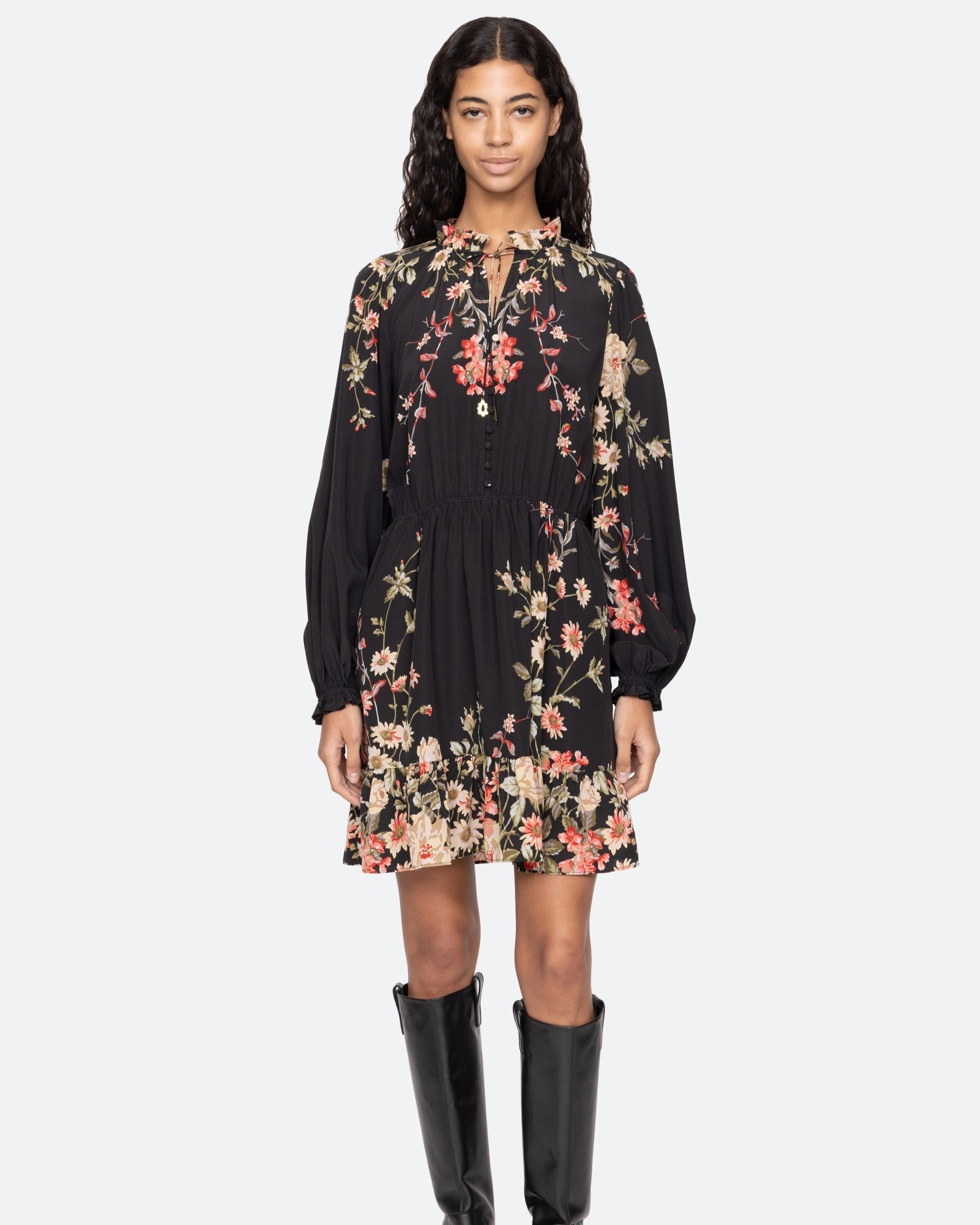 Woman wearing a black floral dress with long sleeves on a white background
