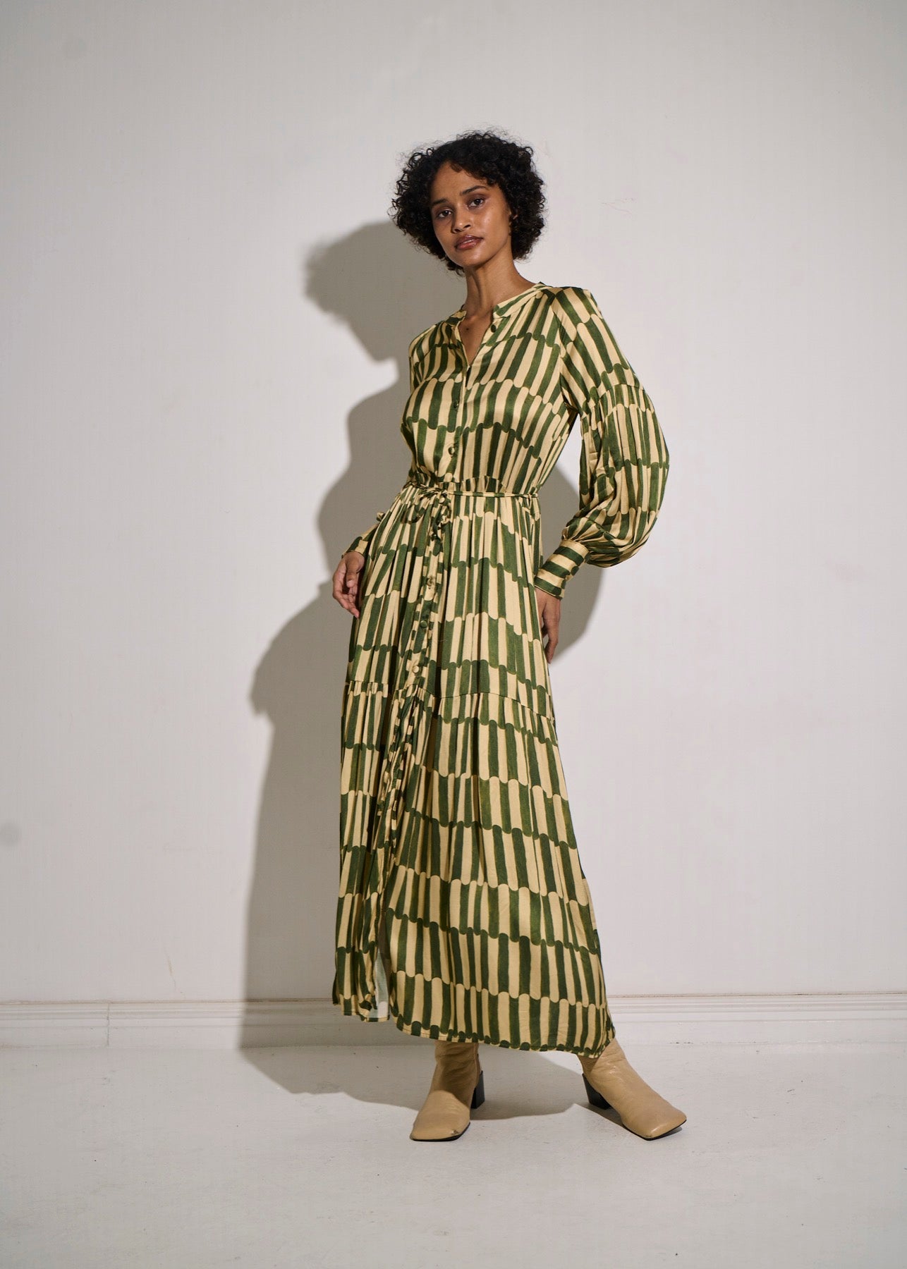 Woman wearing a green and white patterned dress against a white background