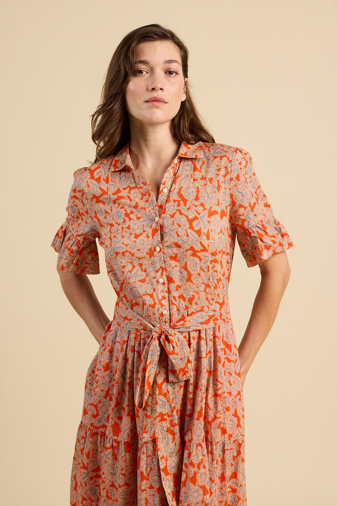 Woman wearing a patterned dress against a beige background