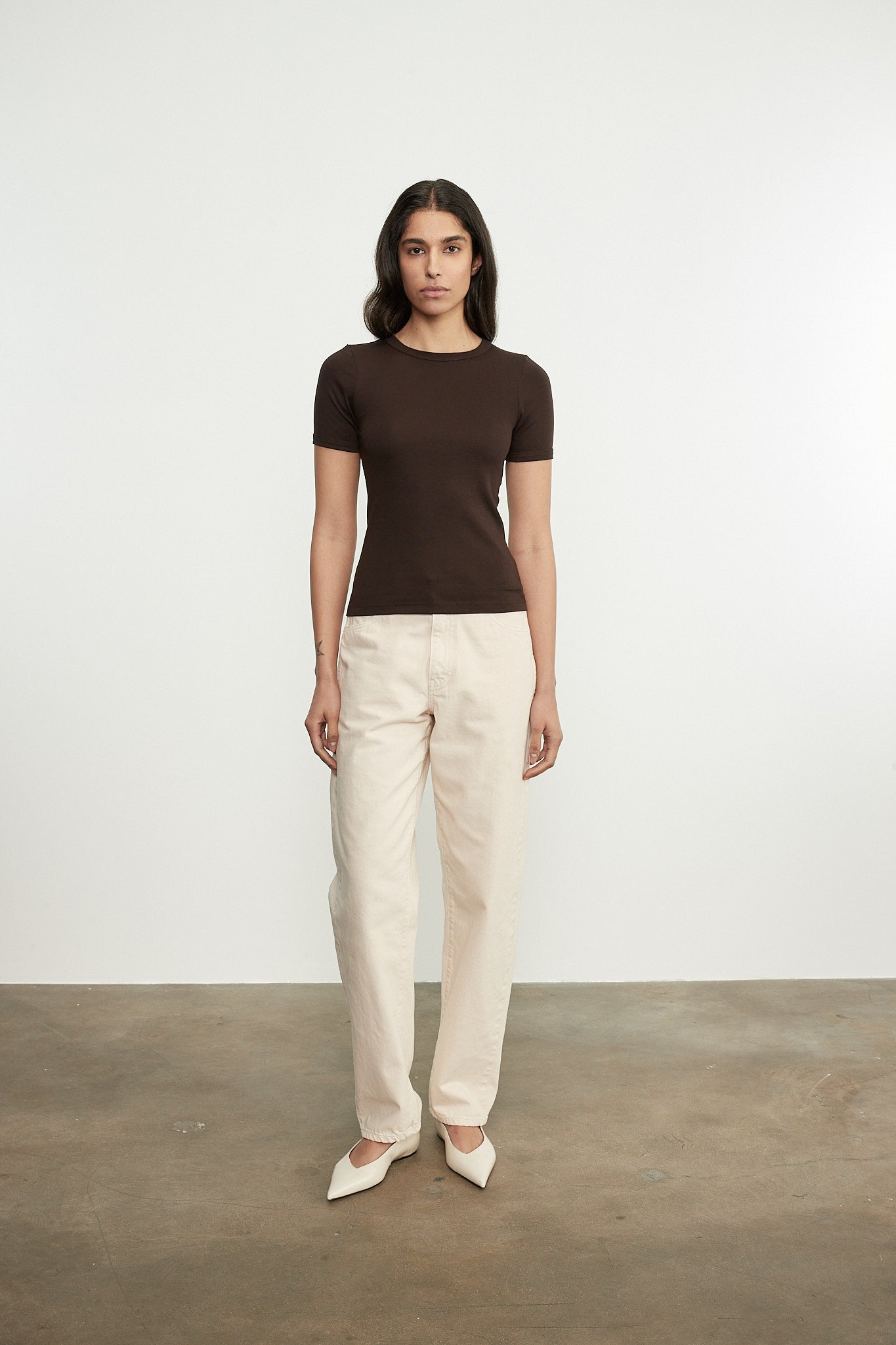 Person wearing a brown top and beige pants on a plain background