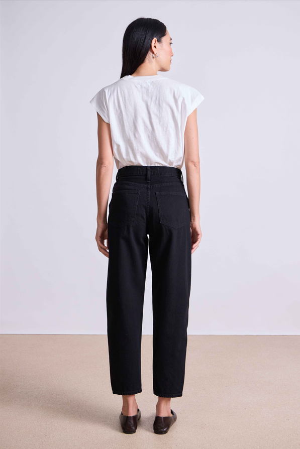 Person wearing a white shirt and black pants against a plain background