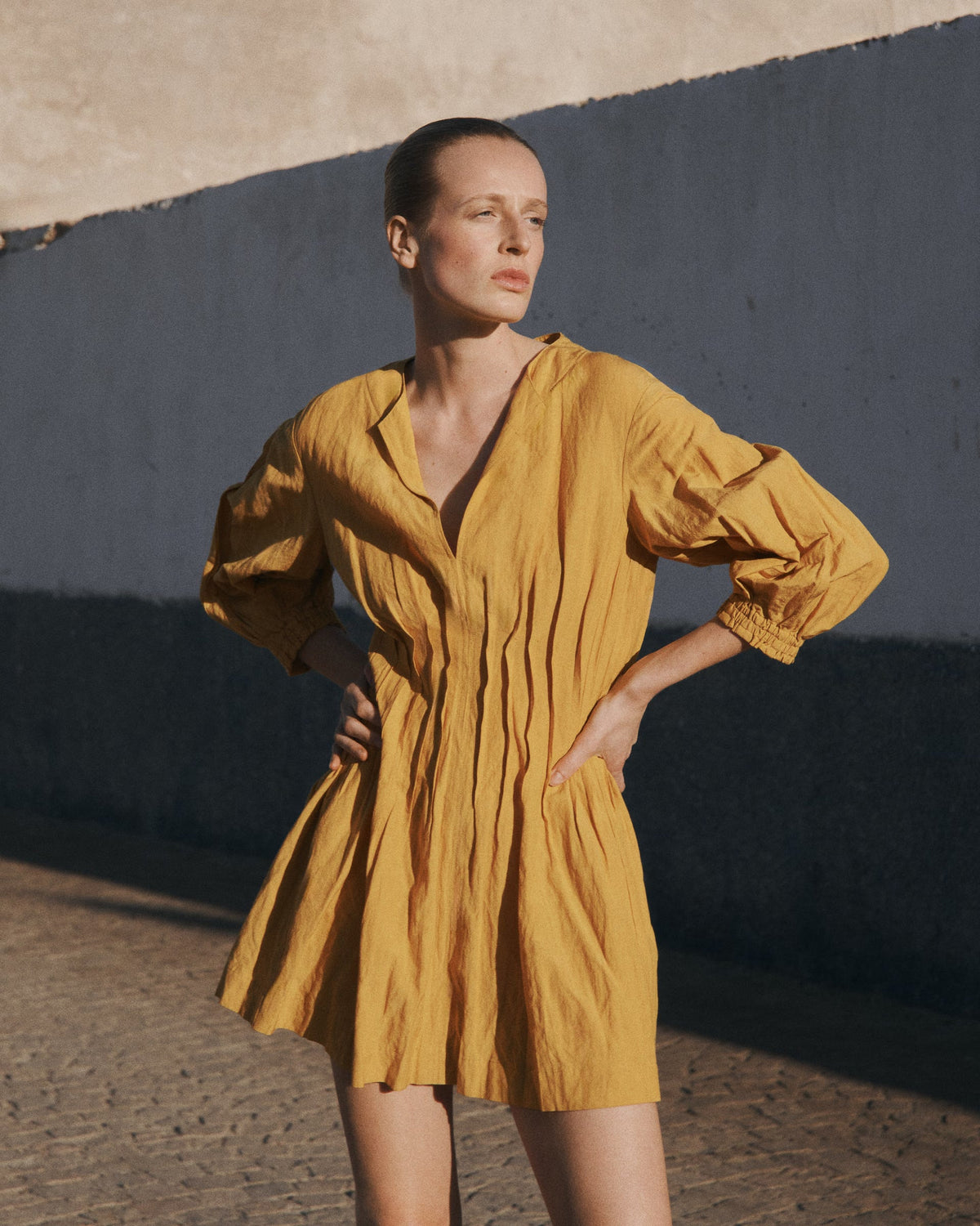 Woman wearing a mustard yellow Apiece Apart mini dress with puffed sleeves
