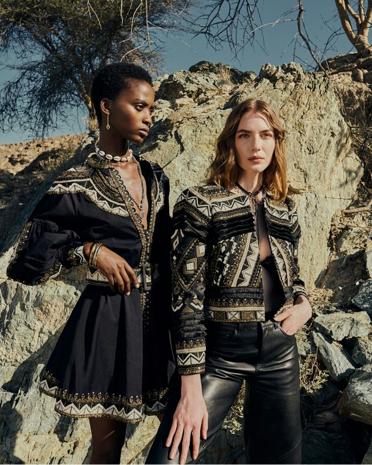 Two models wearing embroidered boho jackets and dress against desert rock formation