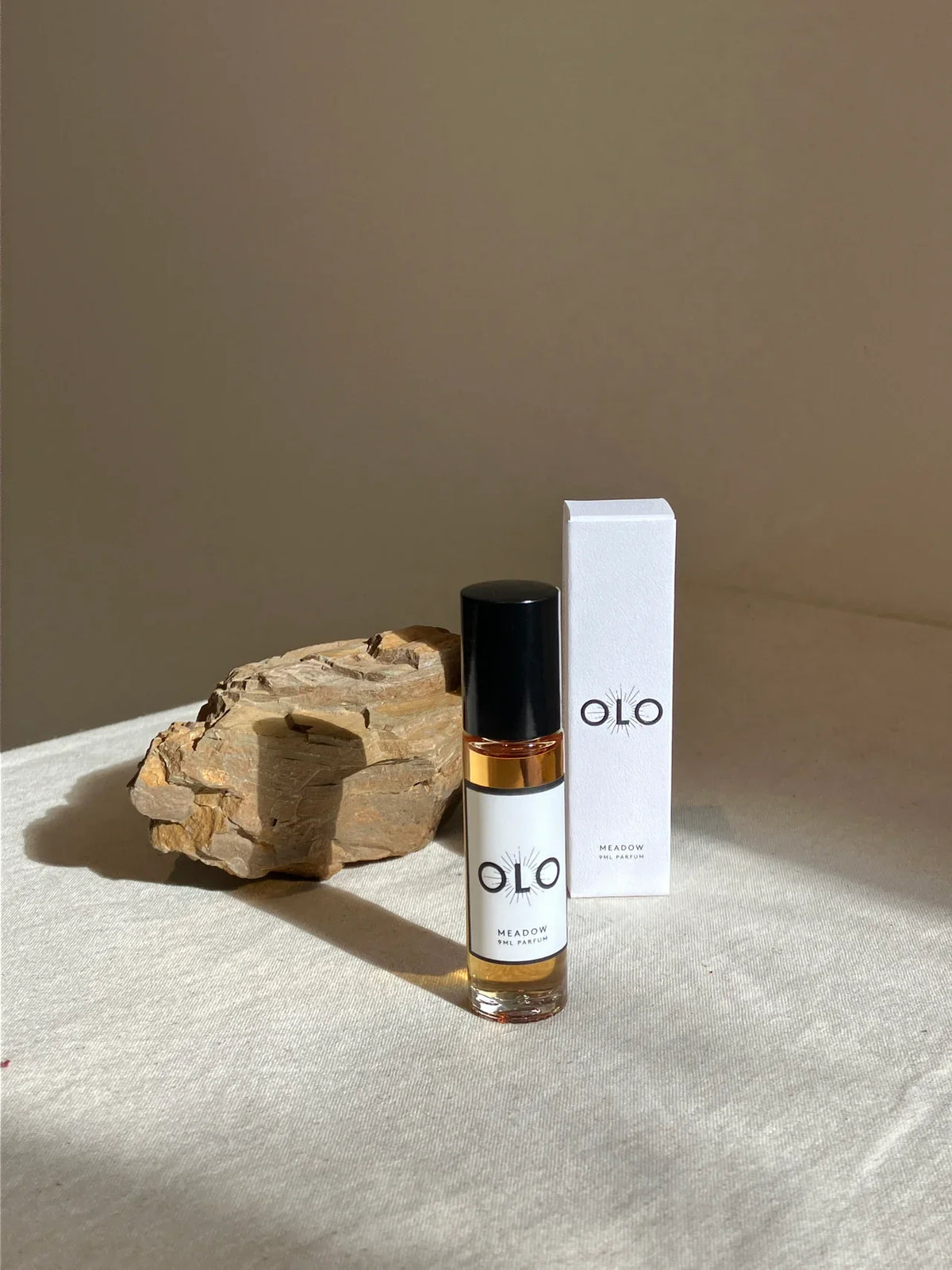 OLO Meadow 9ml parfum bottle and box beside a textured rock