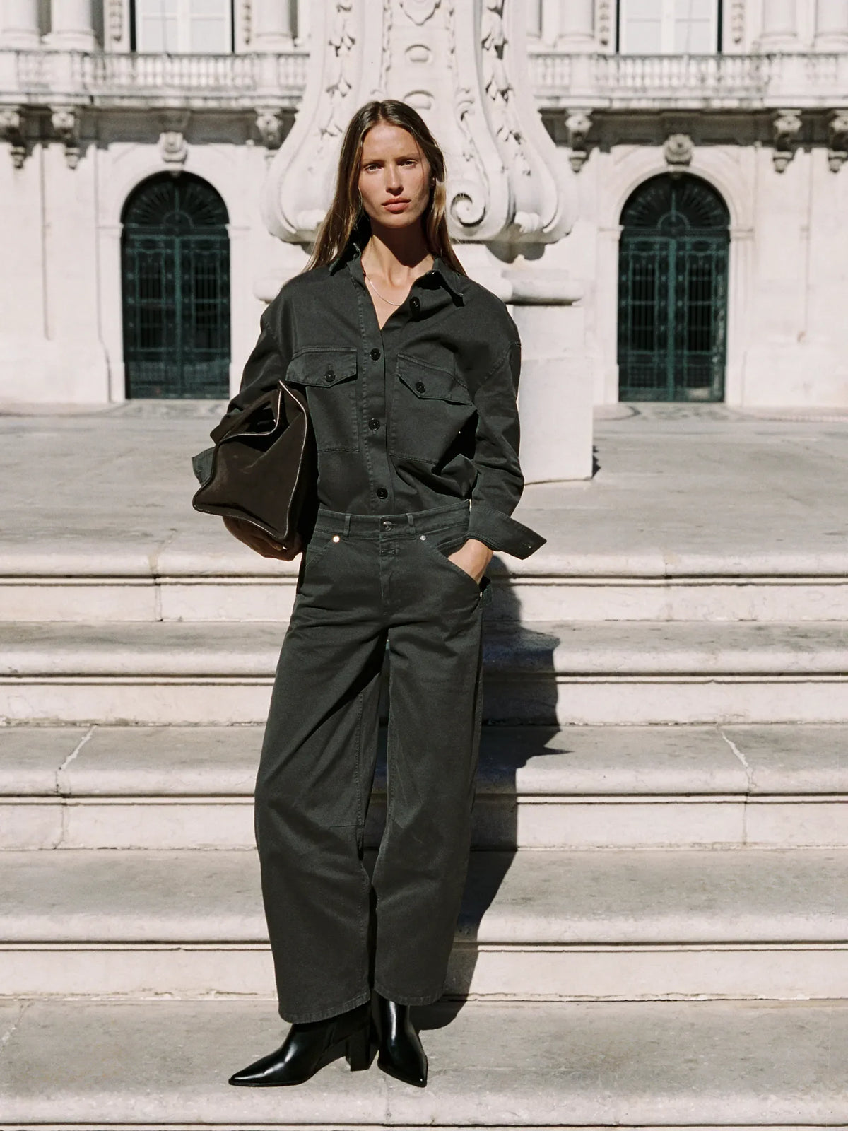 Woman in olive green utility shirt and wide-leg jeans on palace steps
