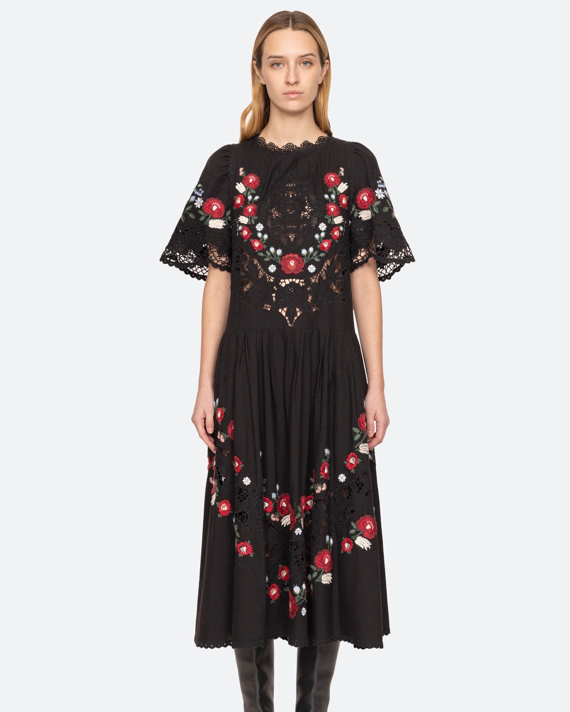 Black dress with red floral embroidery worn by a model on a white background