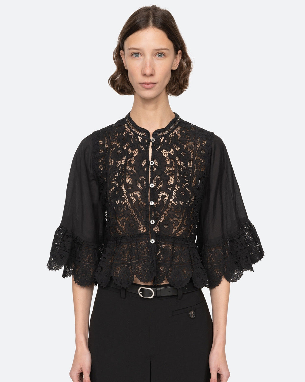 Woman wearing a black lace top with a plain background
