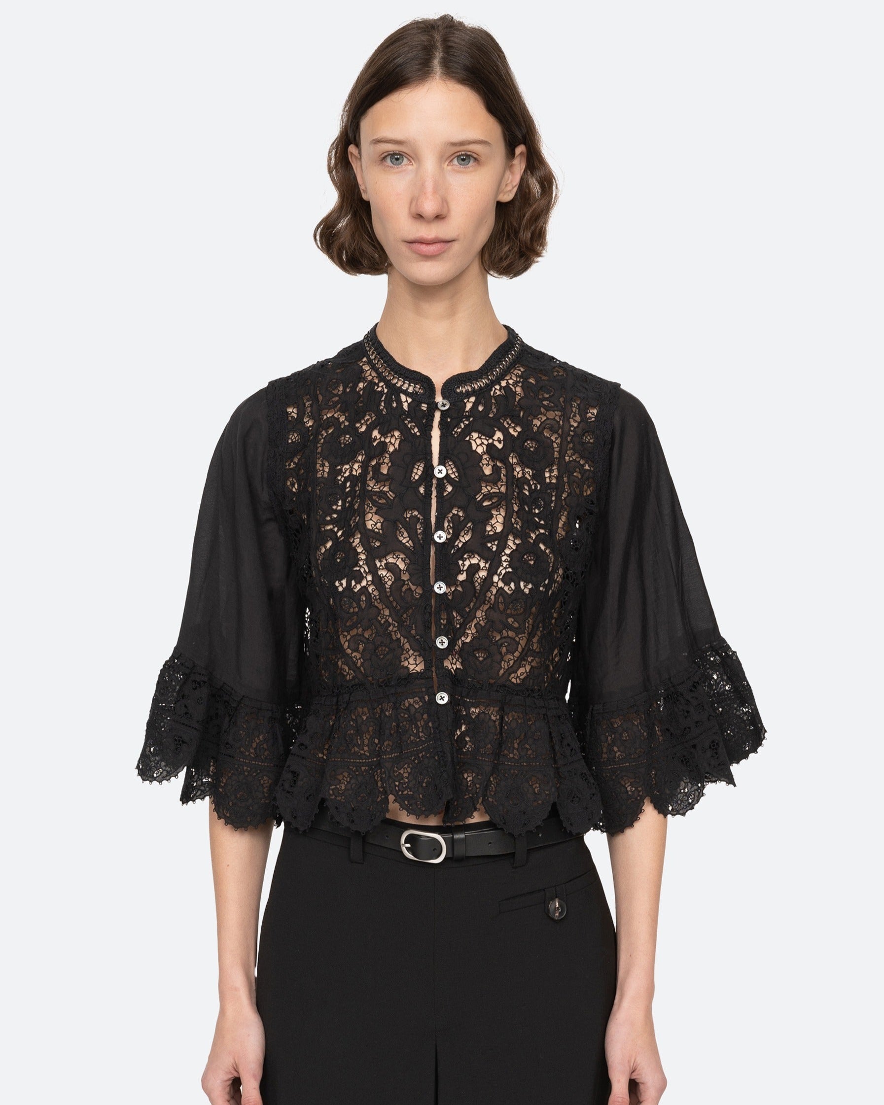 Woman wearing a black lace top with a plain background