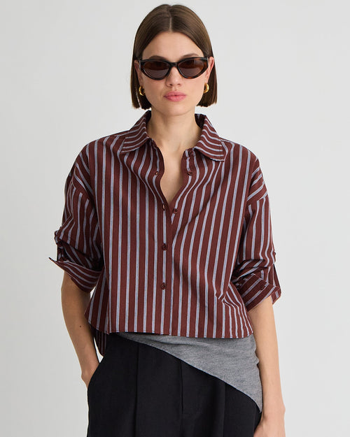 Woman wearing a striped shirt, sunglasses, and black pants on a white background
