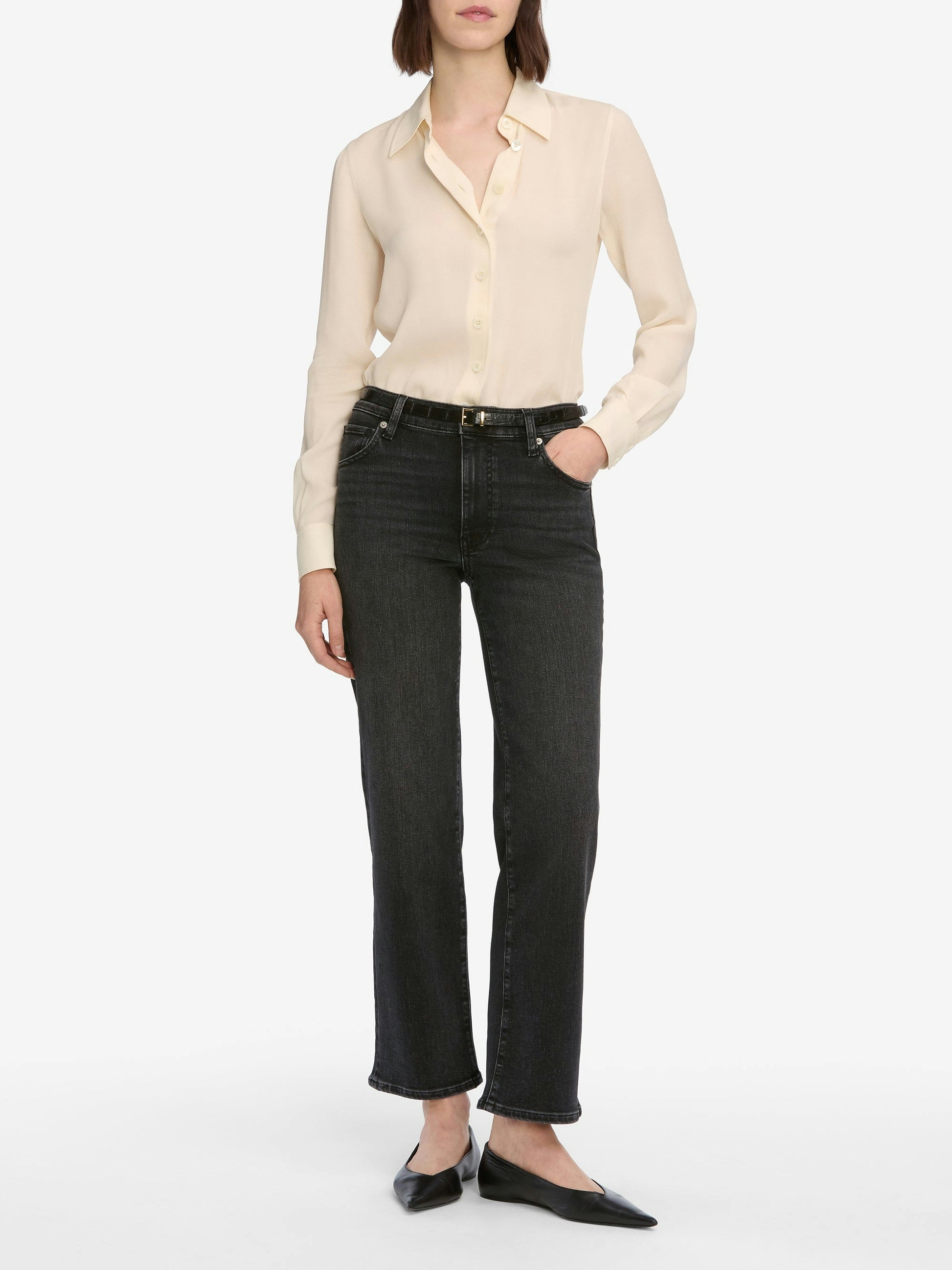Person wearing a beige blouse and black jeans on a white background
