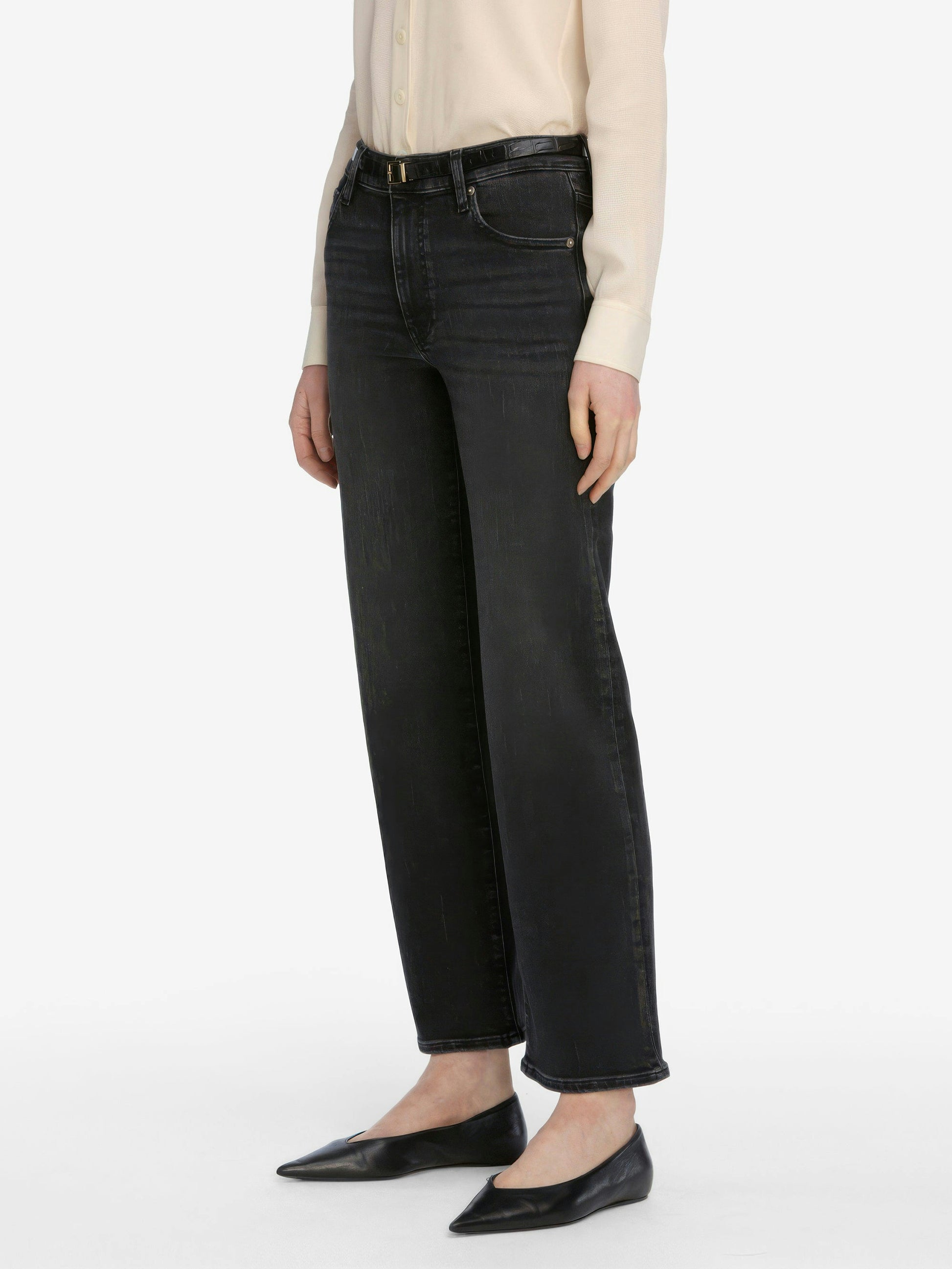 Person wearing black straight-leg jeans on a white background