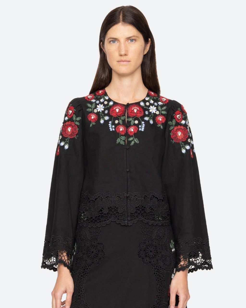 Black embroidered dress worn by a model on a white background