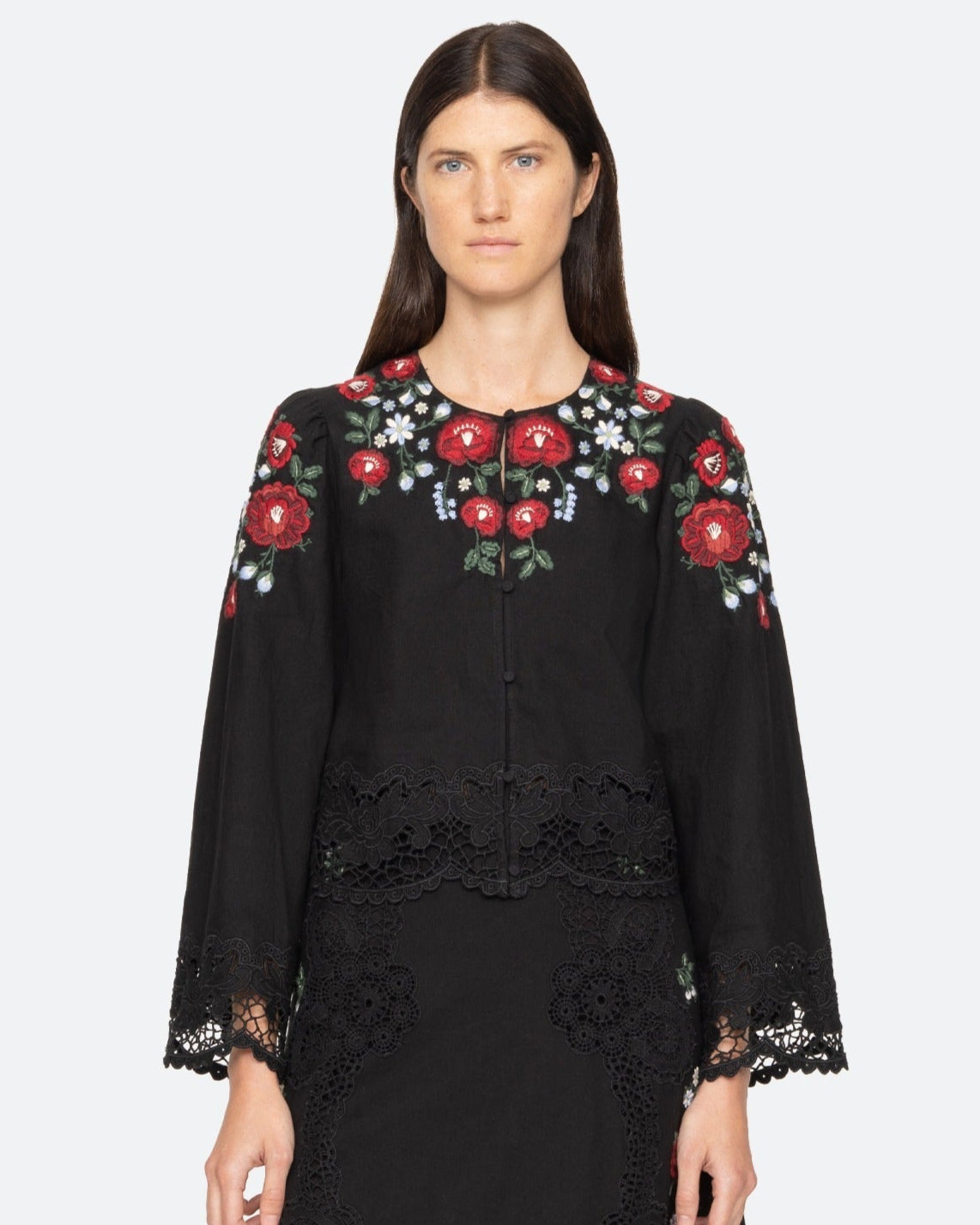 Black embroidered dress worn by a model on a white background