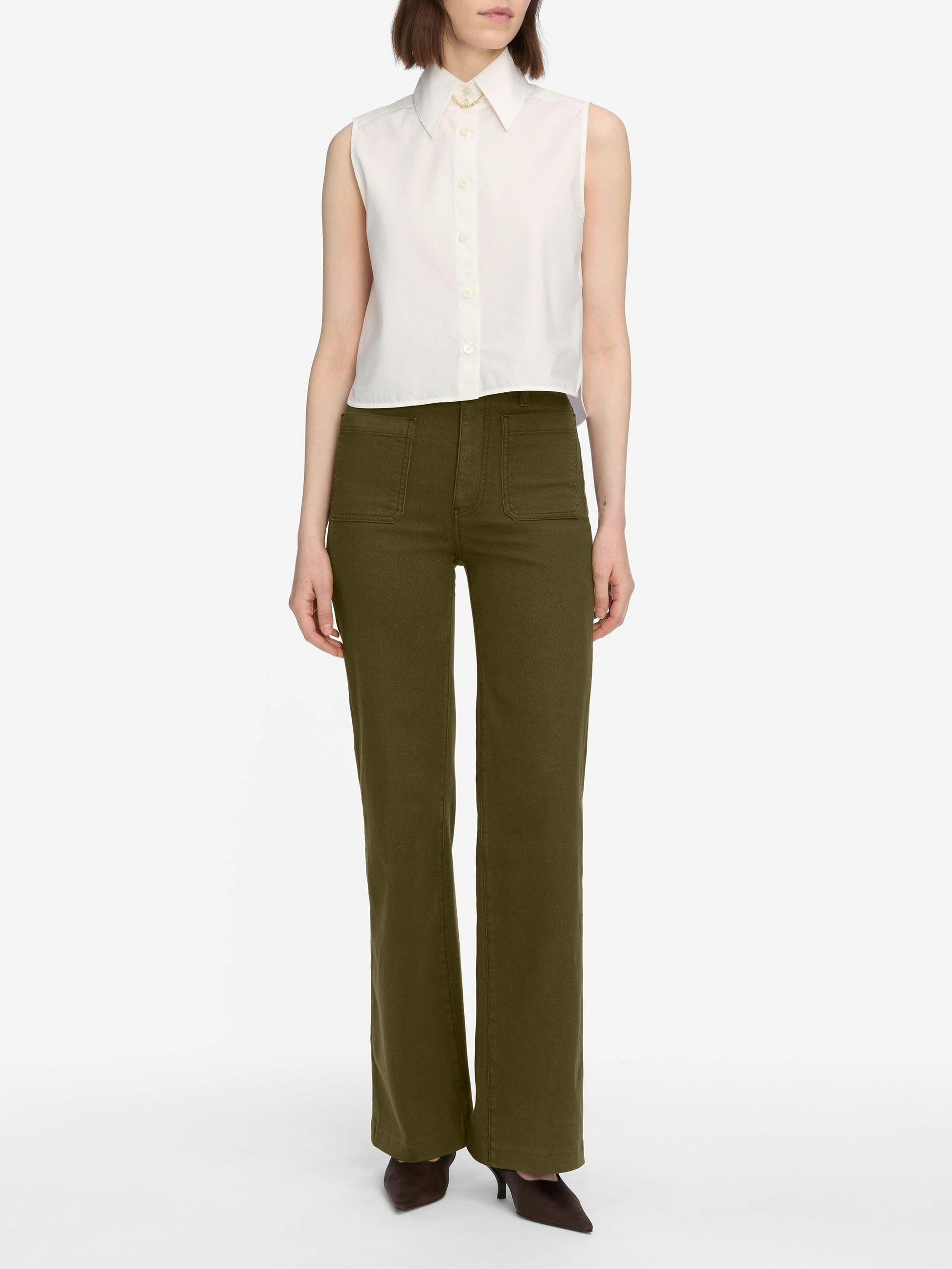 Woman wearing a white sleeveless blouse and green pants on a white background