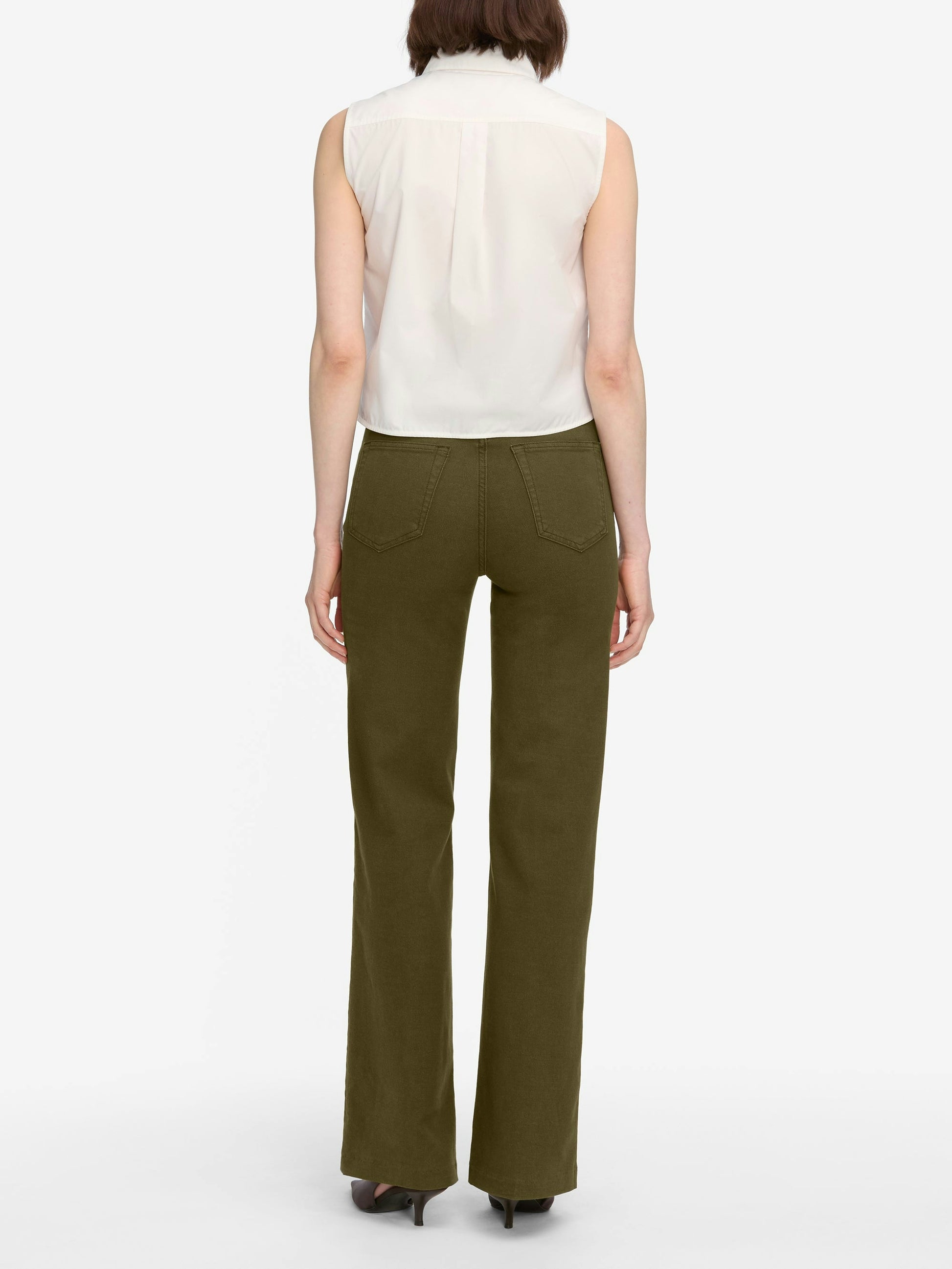 Woman wearing a white sleeveless top and olive green pants on a white background