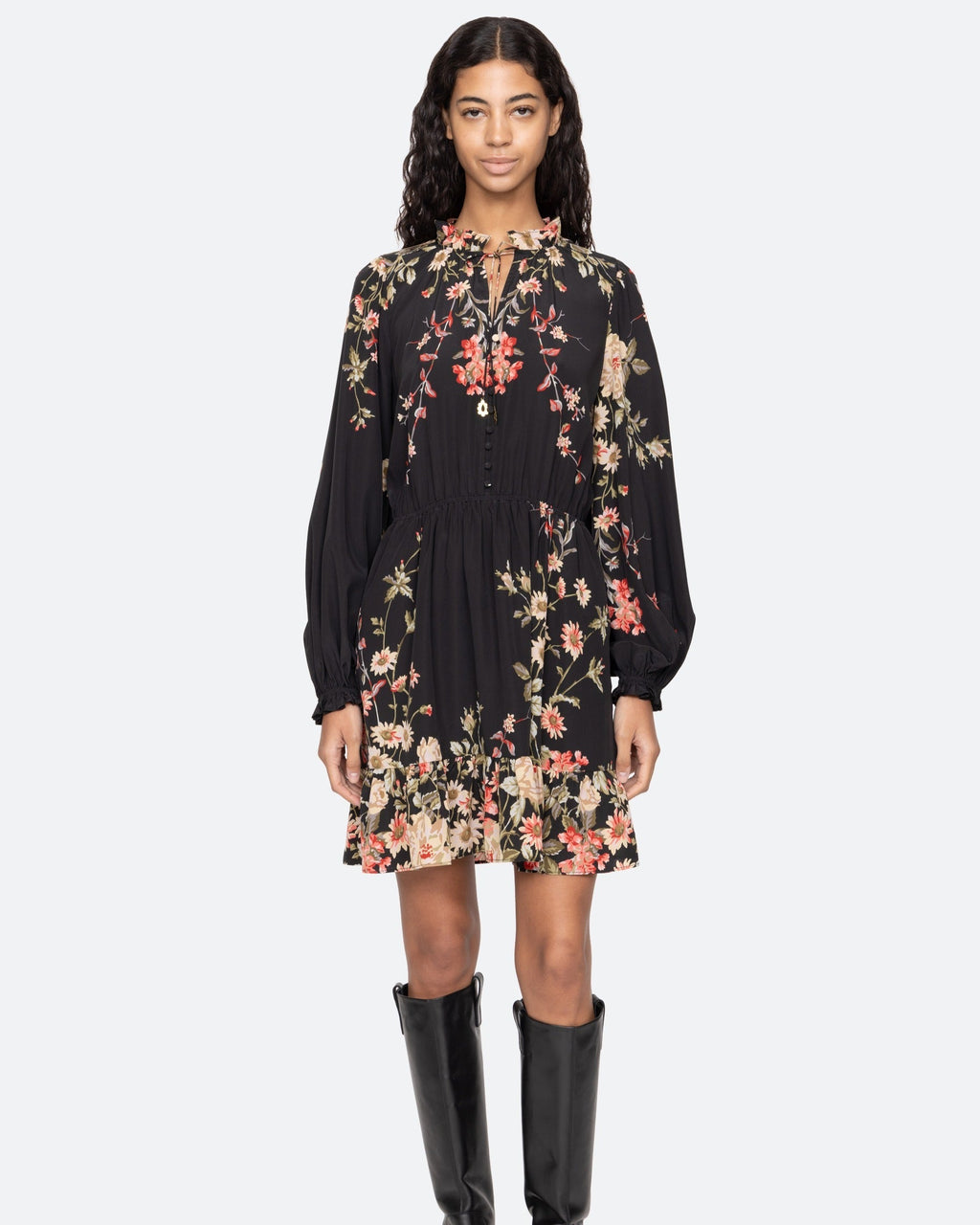 Woman wearing a black floral dress with long sleeves on a white background