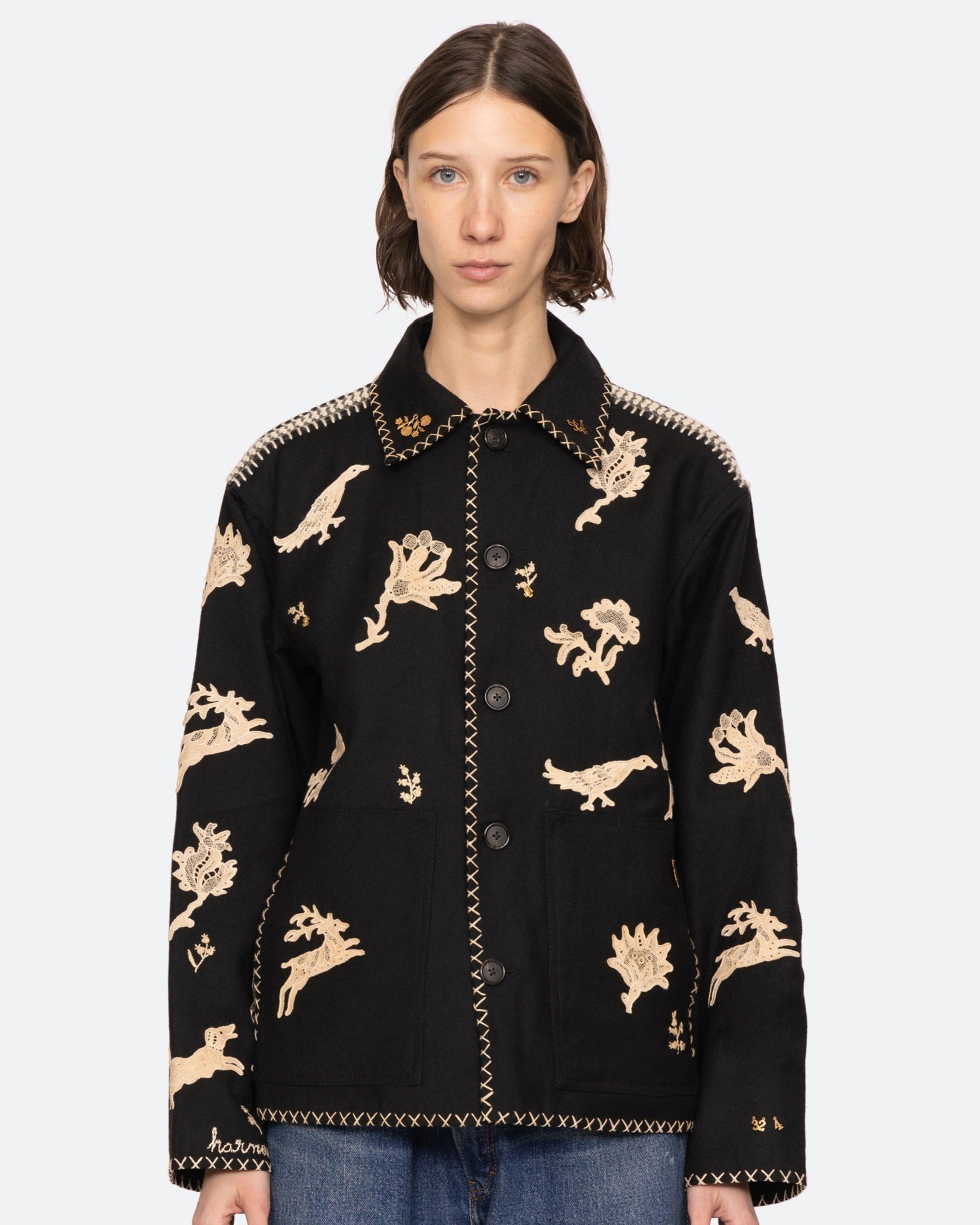 Woman wearing a black jacket with gold animal patterns on a white background