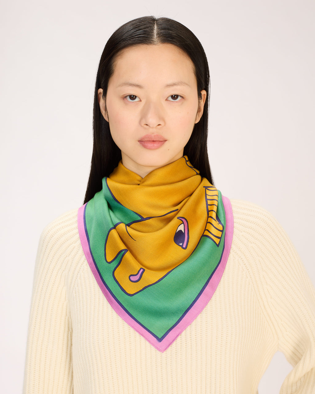Woman wearing a colorful scarf with a fish design on a plain background