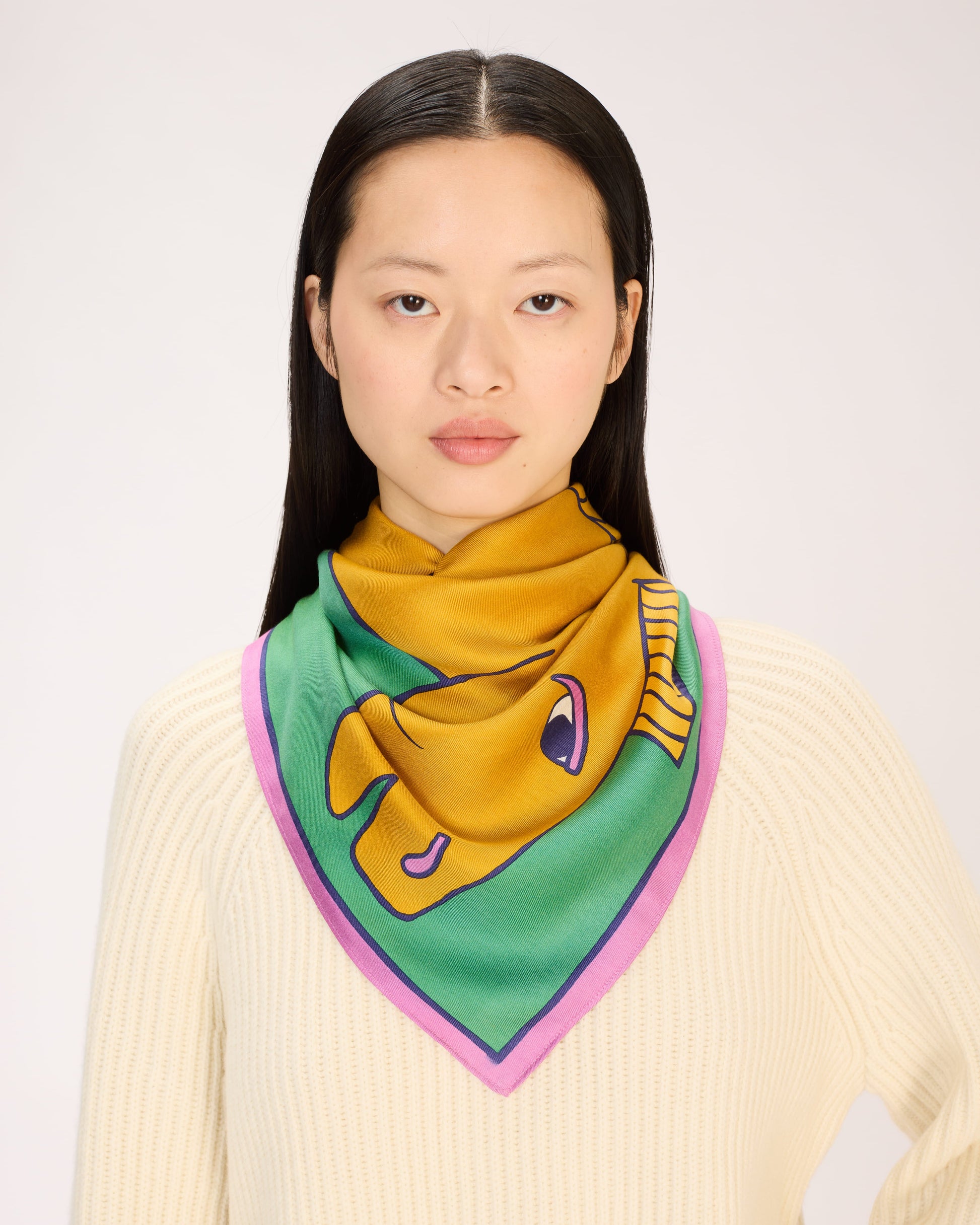 Woman wearing a colorful scarf with a fish design on a plain background