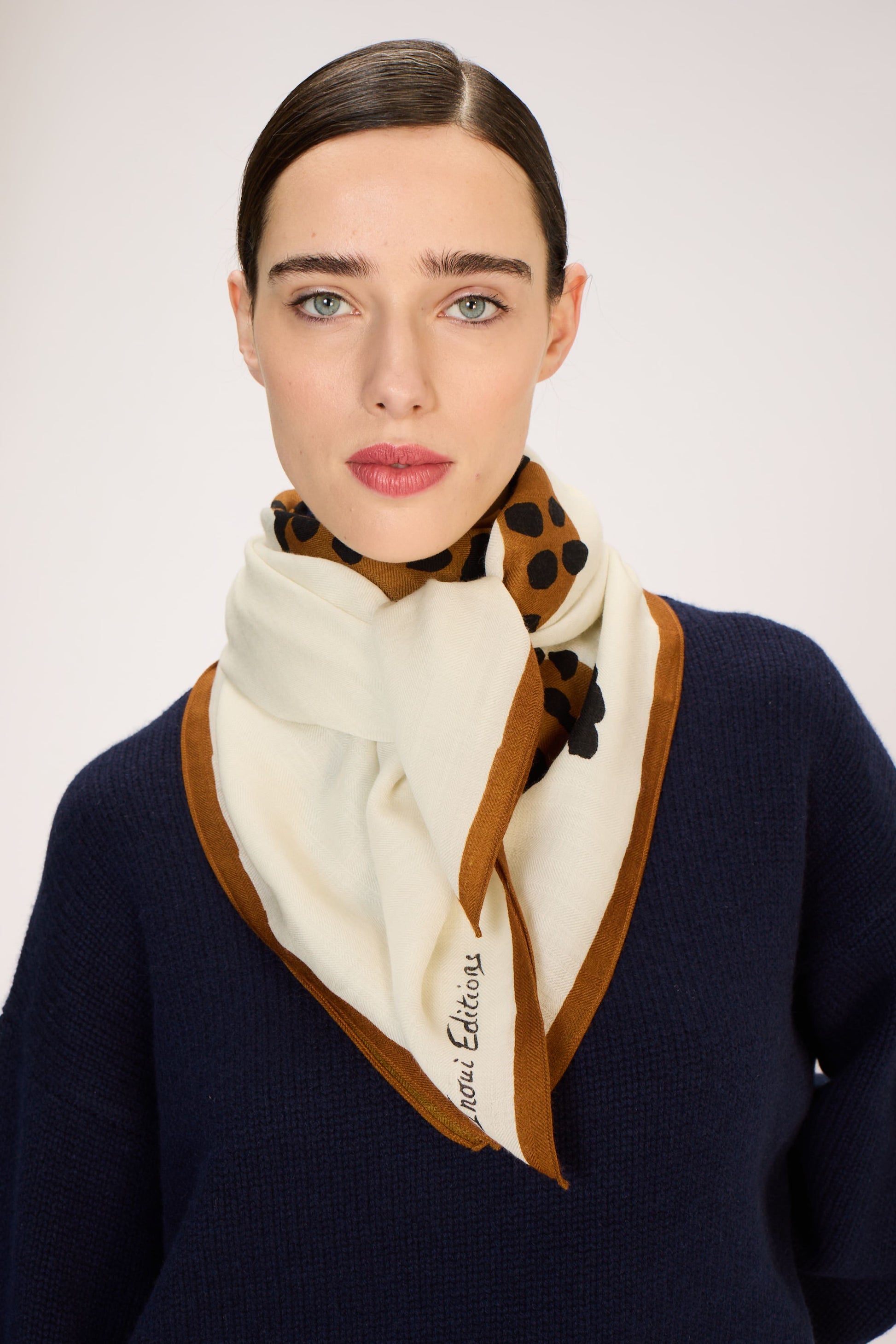 Woman wearing a patterned scarf with a plain background