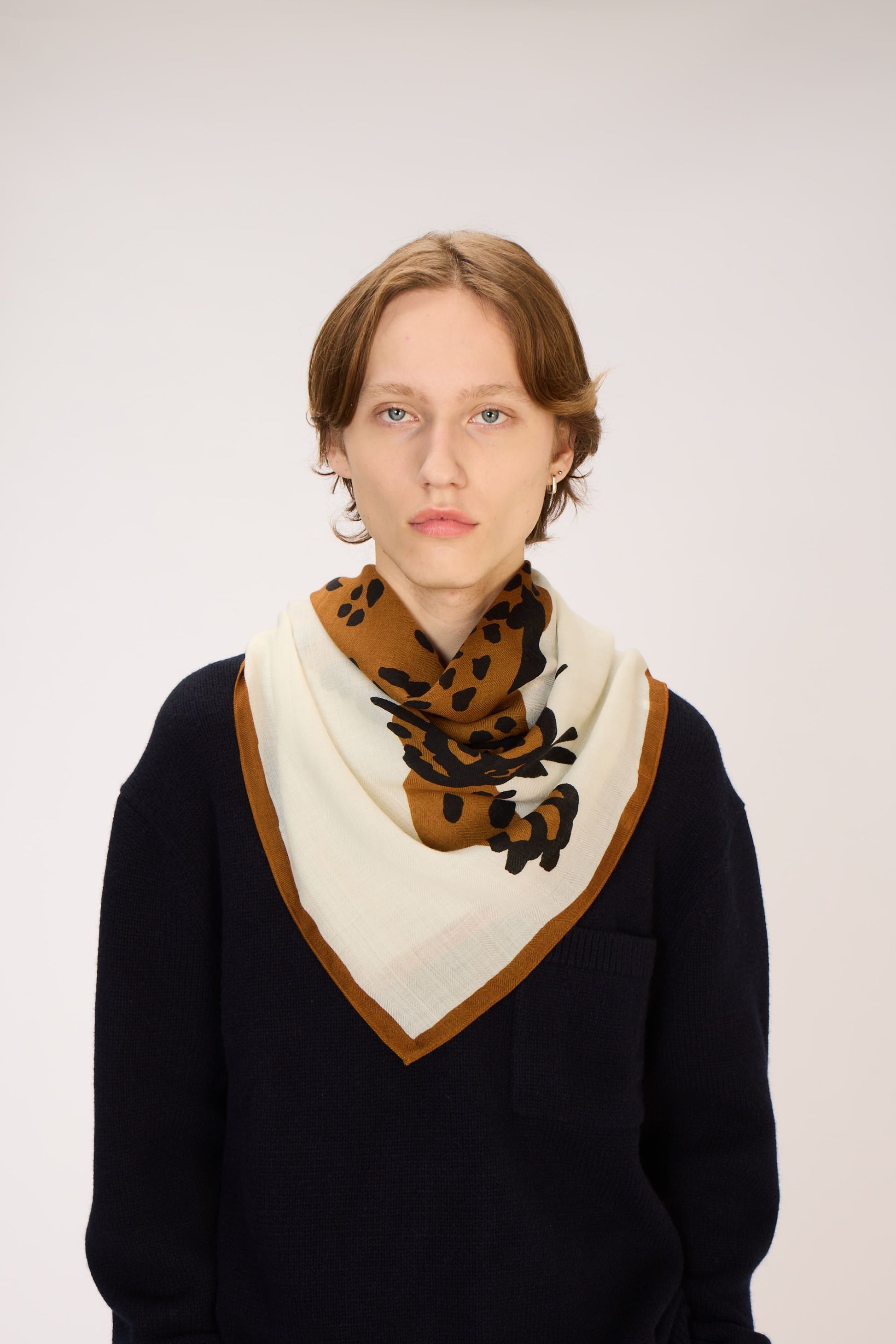 Person wearing a black sweater and a patterned scarf on a white background