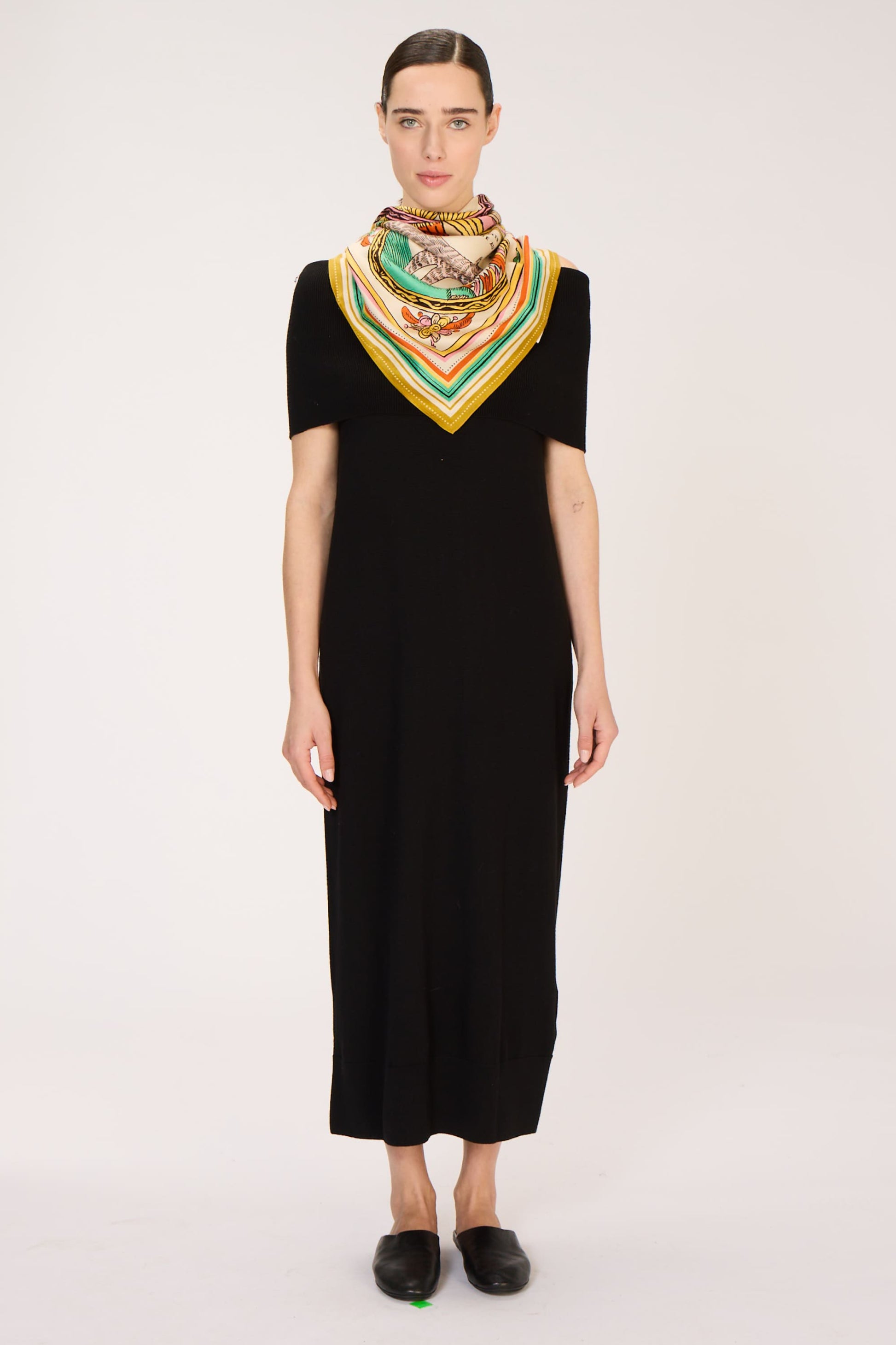Woman wearing a black dress and colorful scarf on a white background