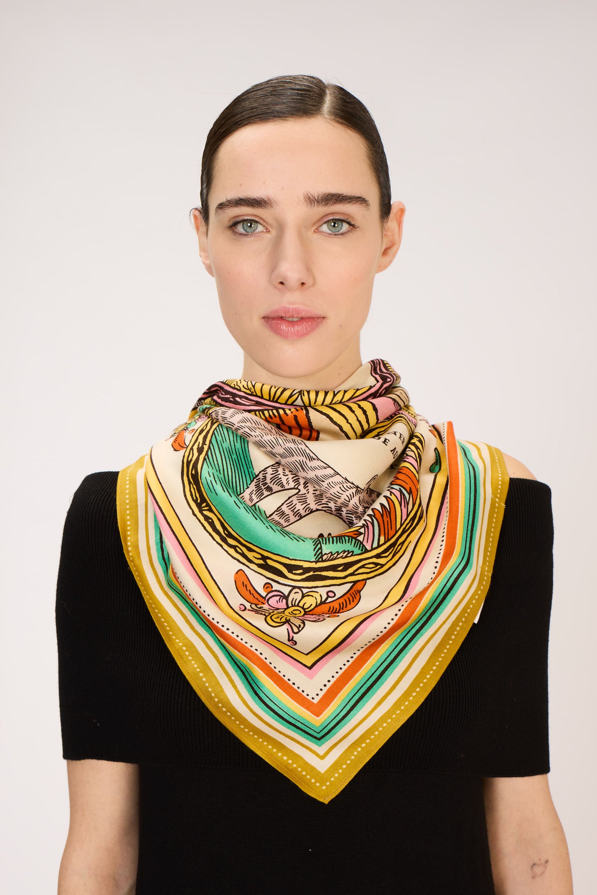 Woman wearing a colorful patterned scarf on a plain background
