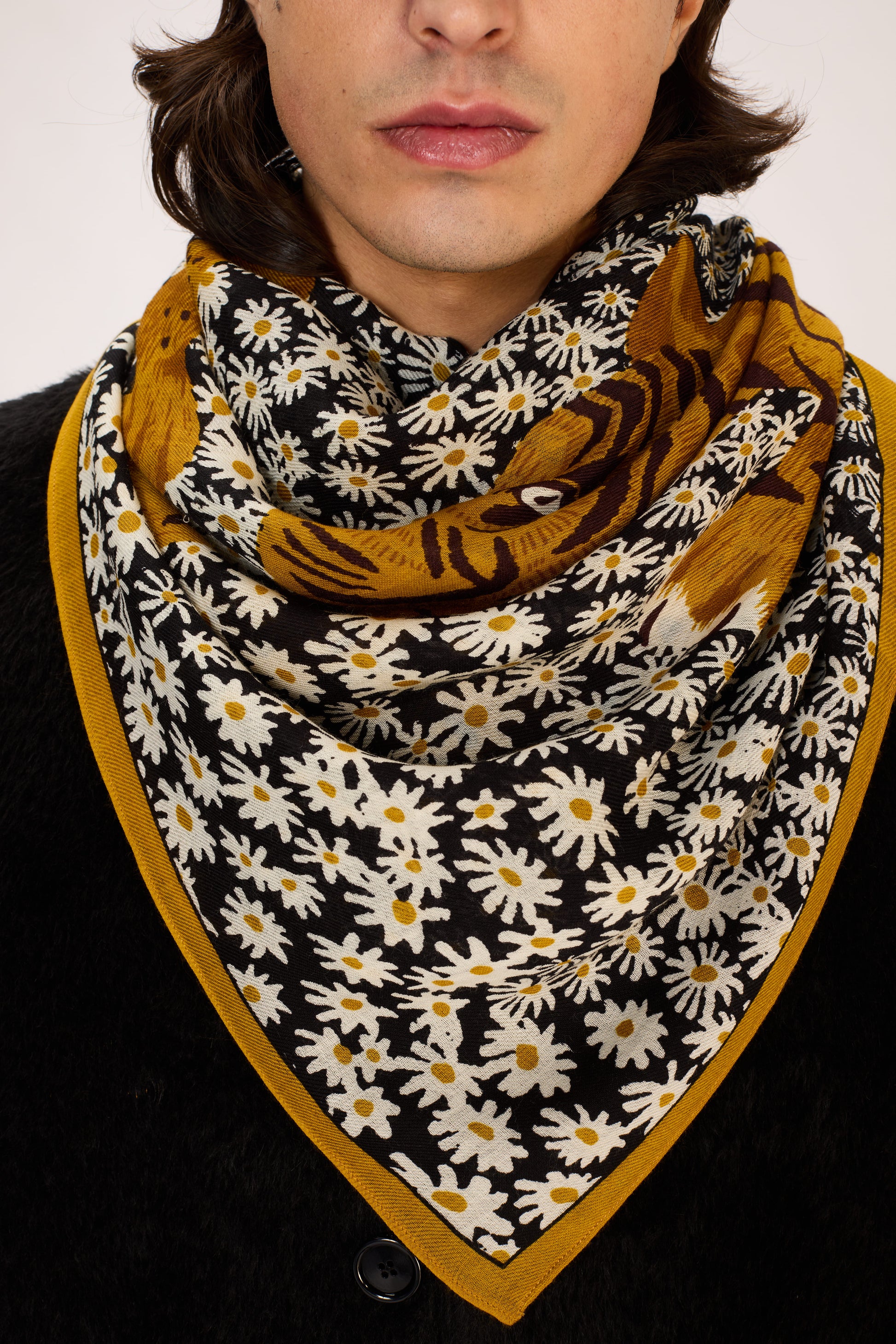 Person wearing a floral and tiger patterned scarf with mustard yellow edges.