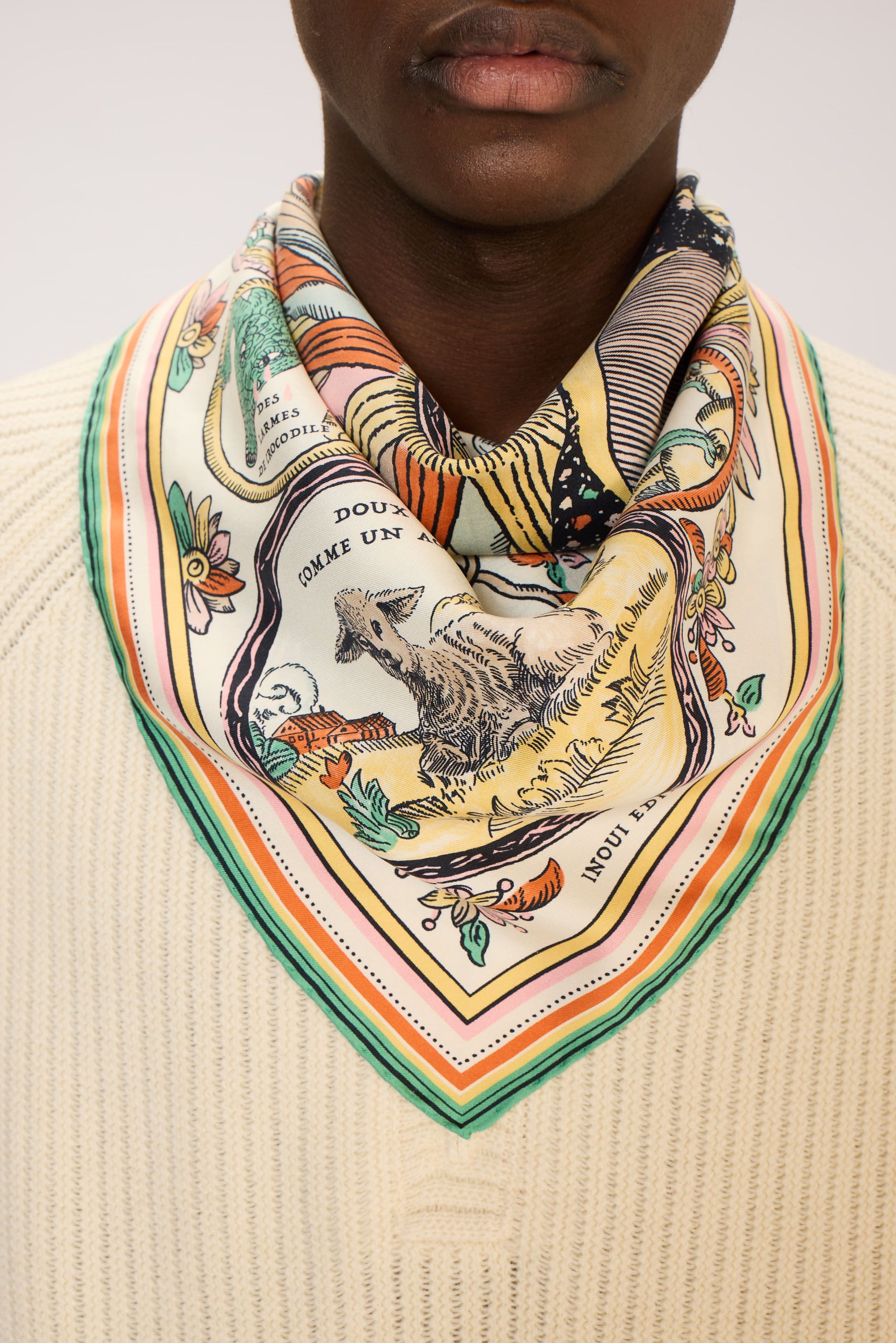 Person wearing a colorful patterned scarf on a plain background