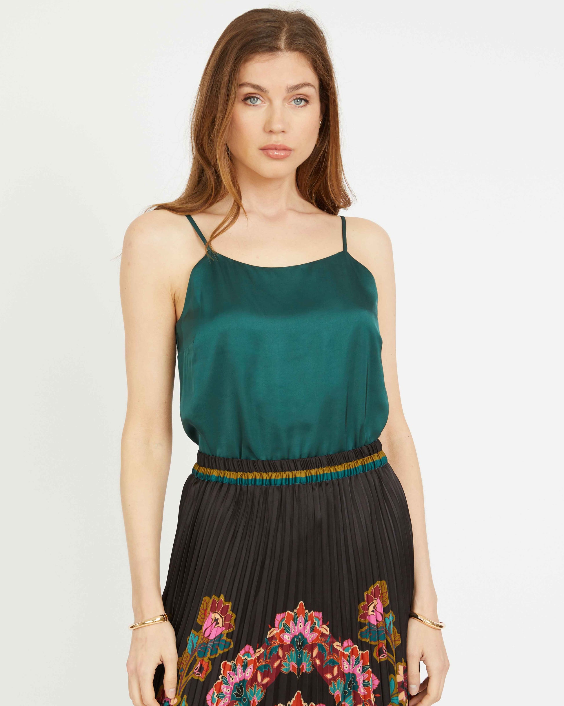 Woman wearing a green top and a colorful skirt on a white background