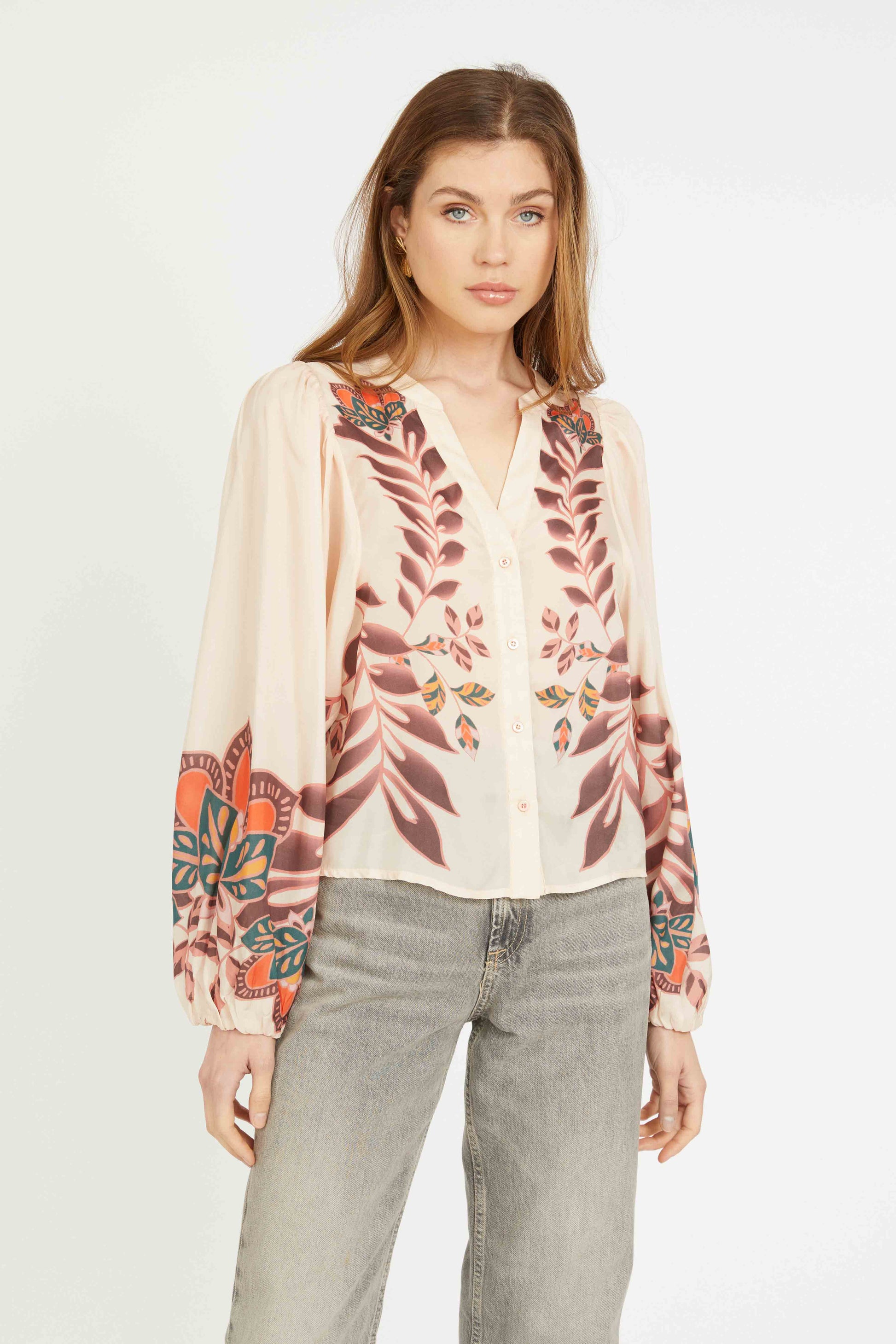 Woman wearing a floral blouse and gray pants on a white background
