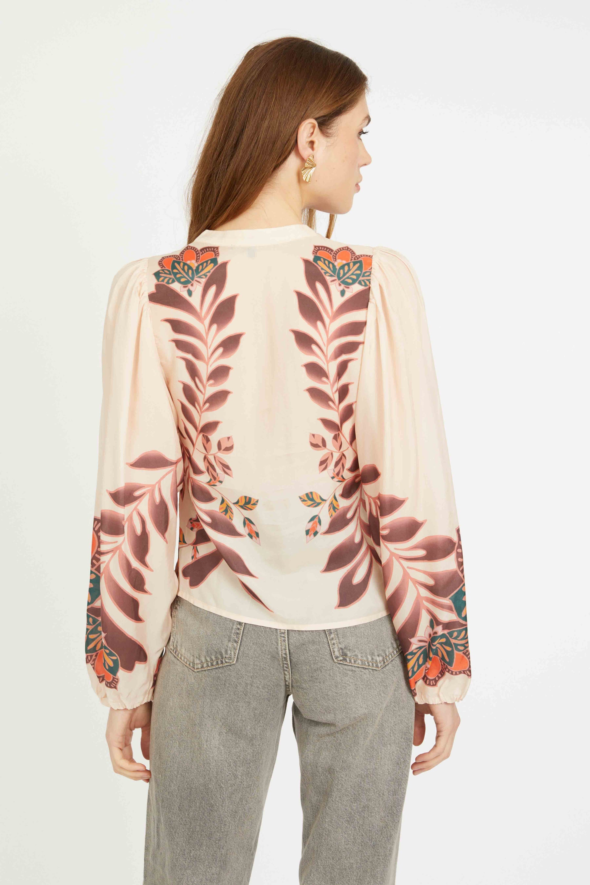 Woman wearing a floral embroidered blouse with a plain background