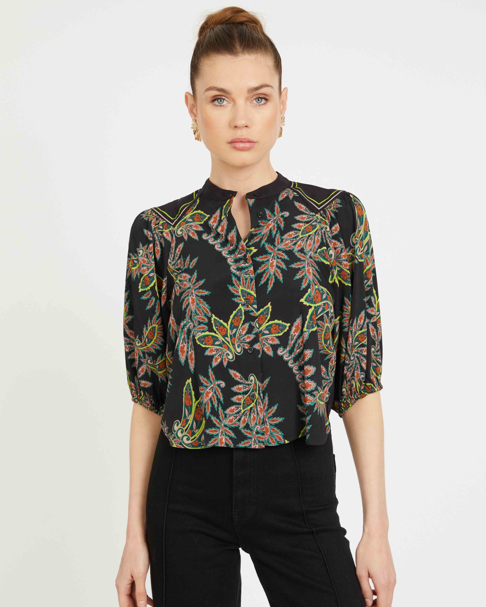 Woman wearing a black floral blouse with a plain background