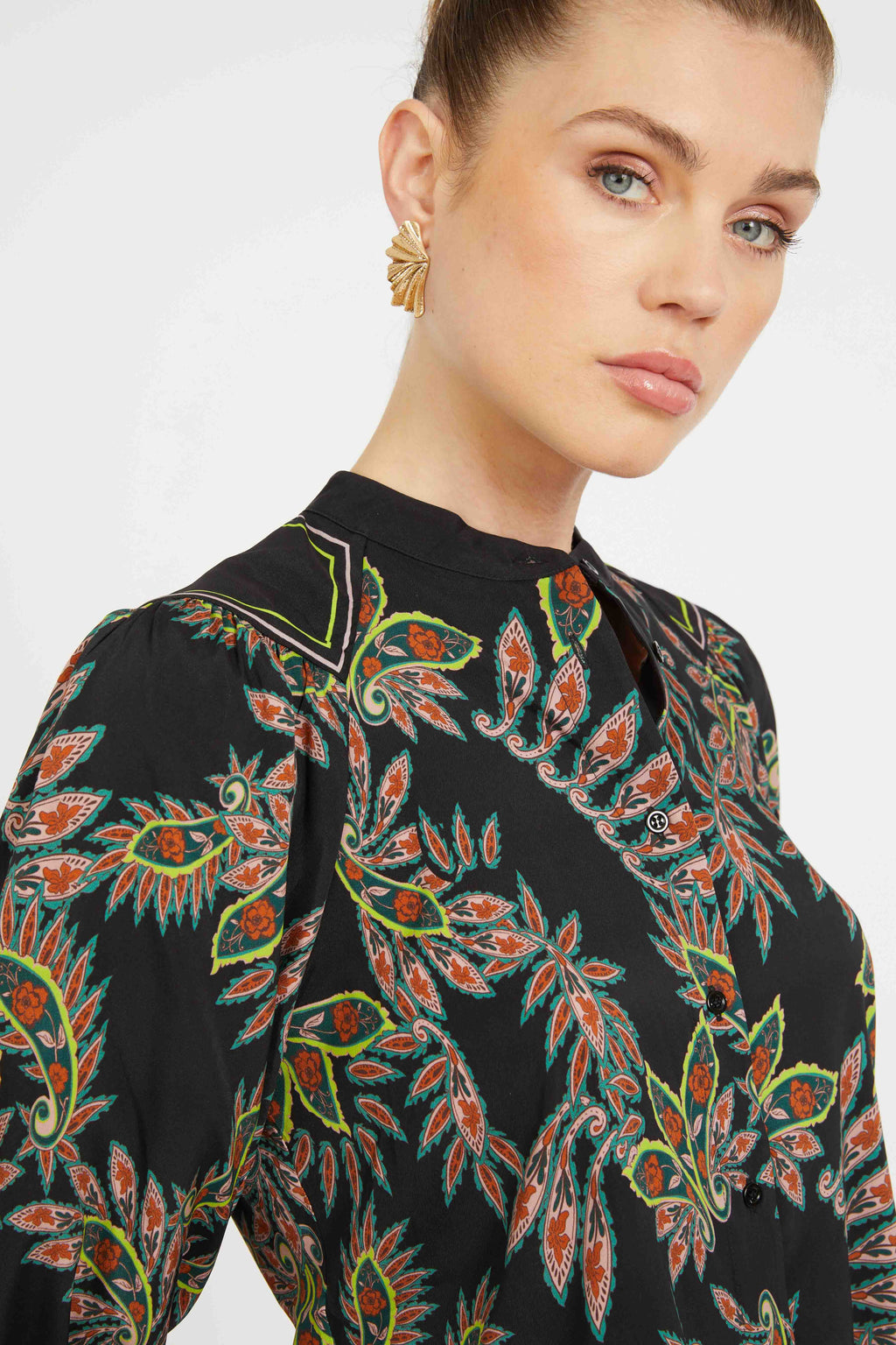 Woman wearing a black patterned blouse with a plain background