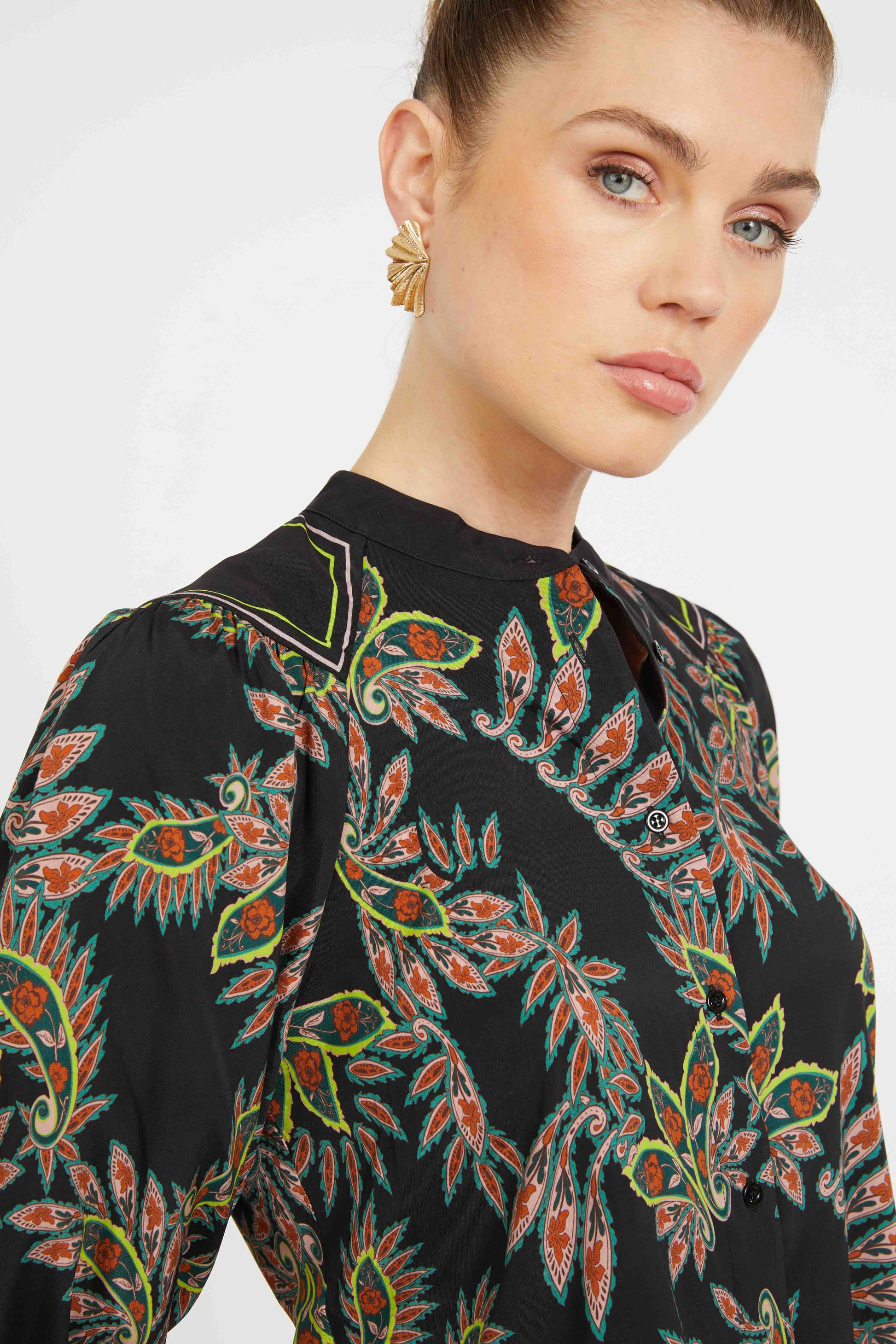 Woman wearing a black patterned blouse with a plain background