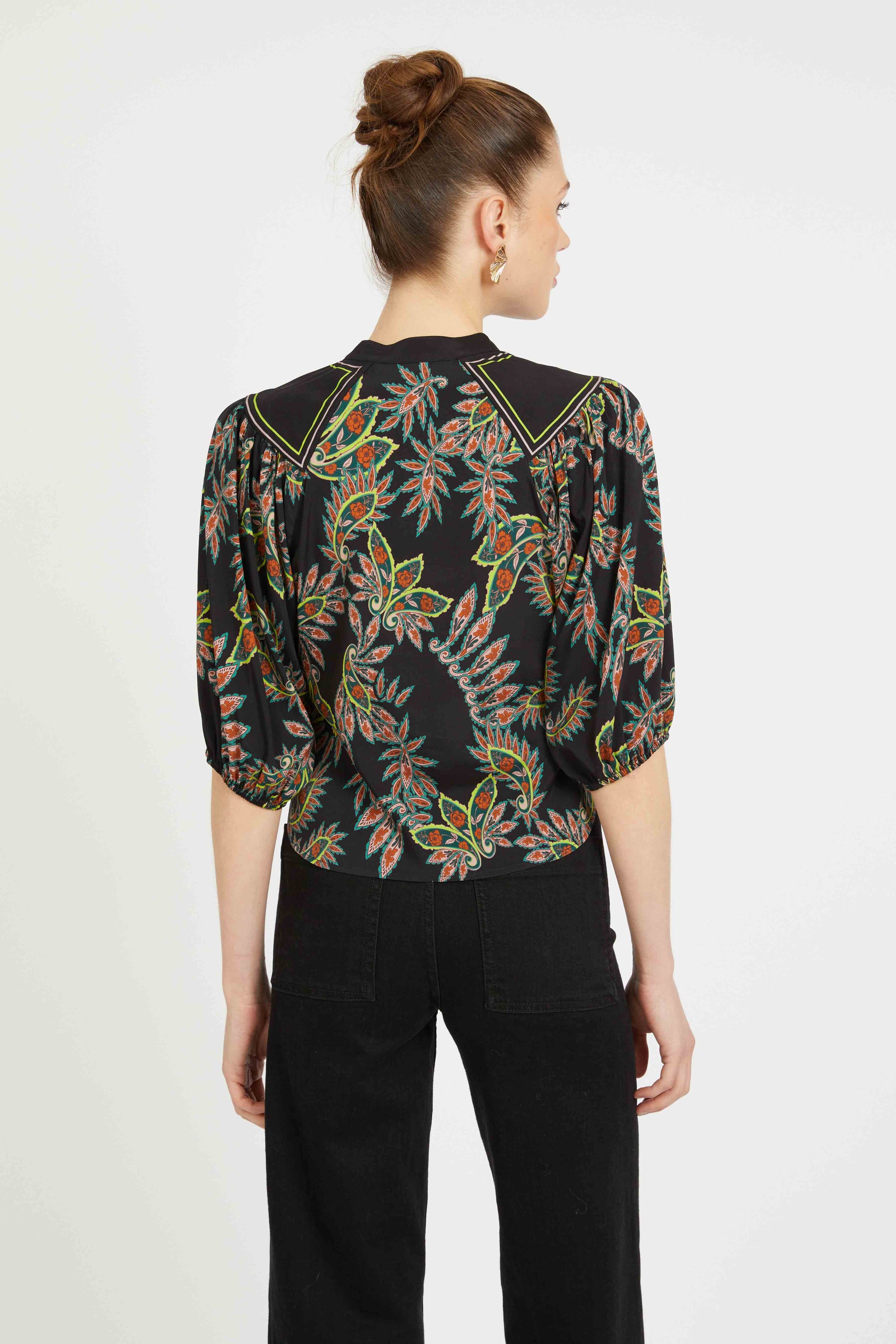 Woman wearing a black floral blouse with a plain background