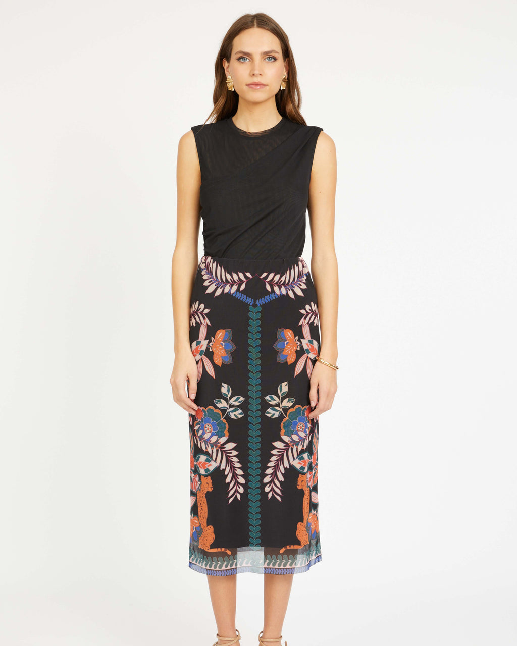 Woman wearing a black sleeveless top and patterned skirt on a white background