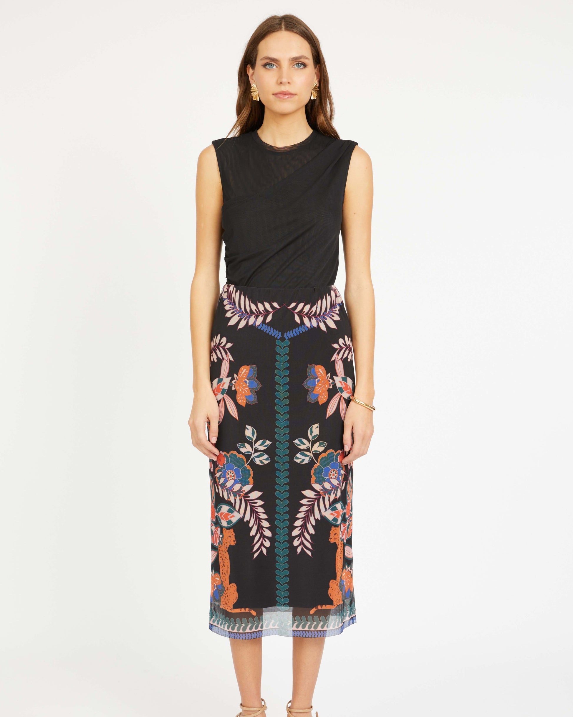 Woman wearing a black sleeveless top and patterned skirt on a white background