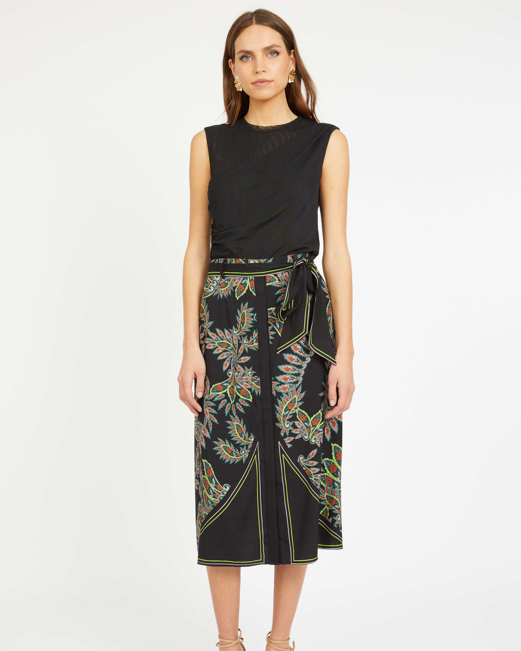 Woman wearing a black sleeveless top and floral skirt on a white background