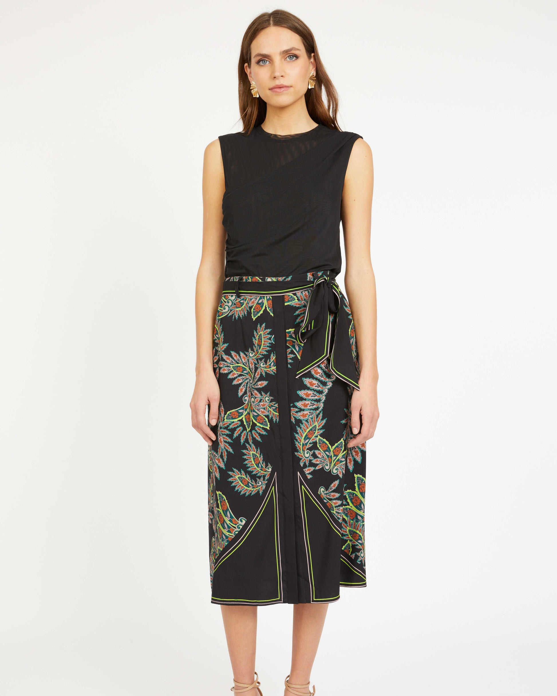 Woman wearing a black sleeveless top and floral skirt on a white background