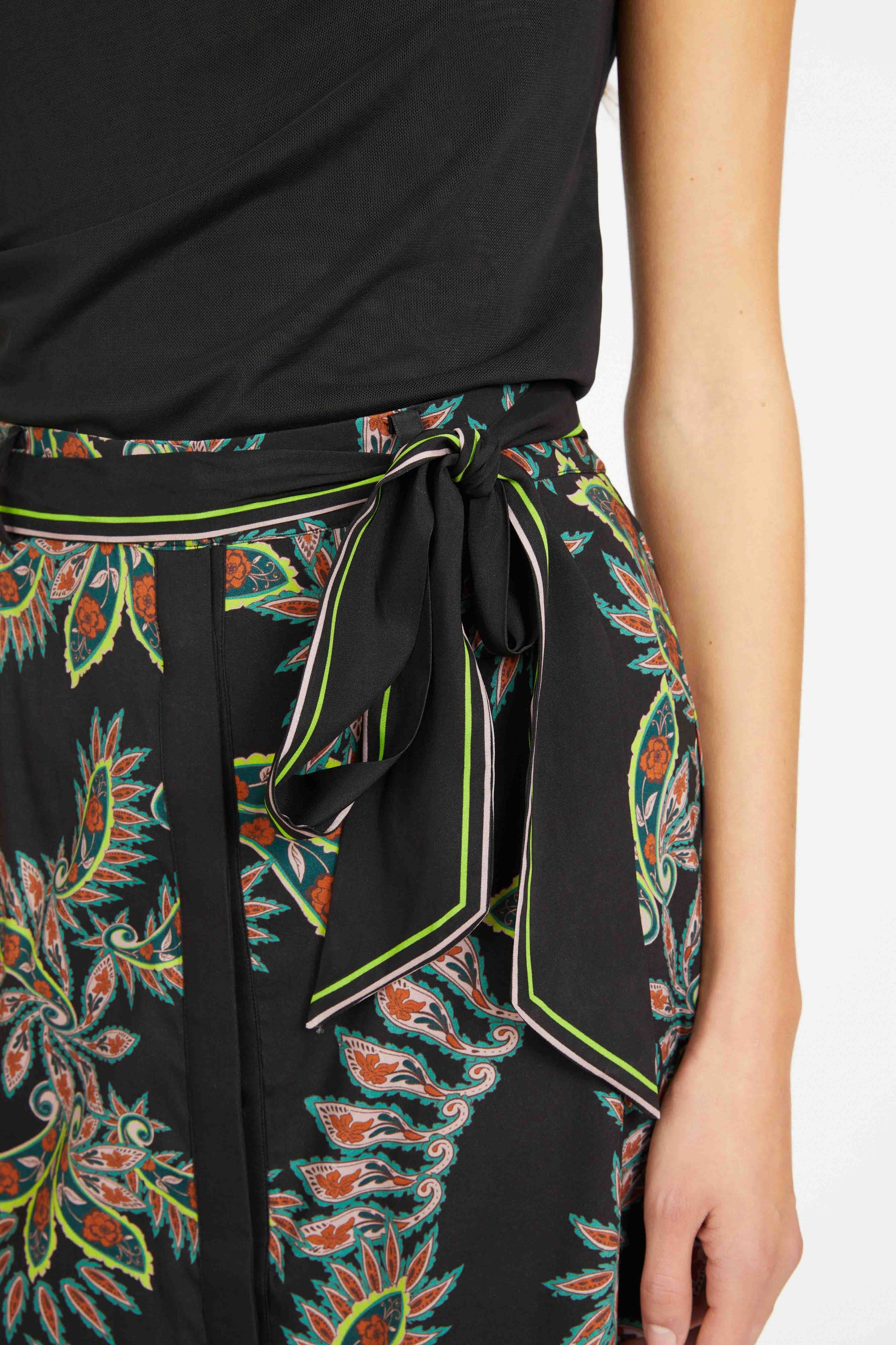 Close-up of a black top with a colorful, patterned skirt on a white background