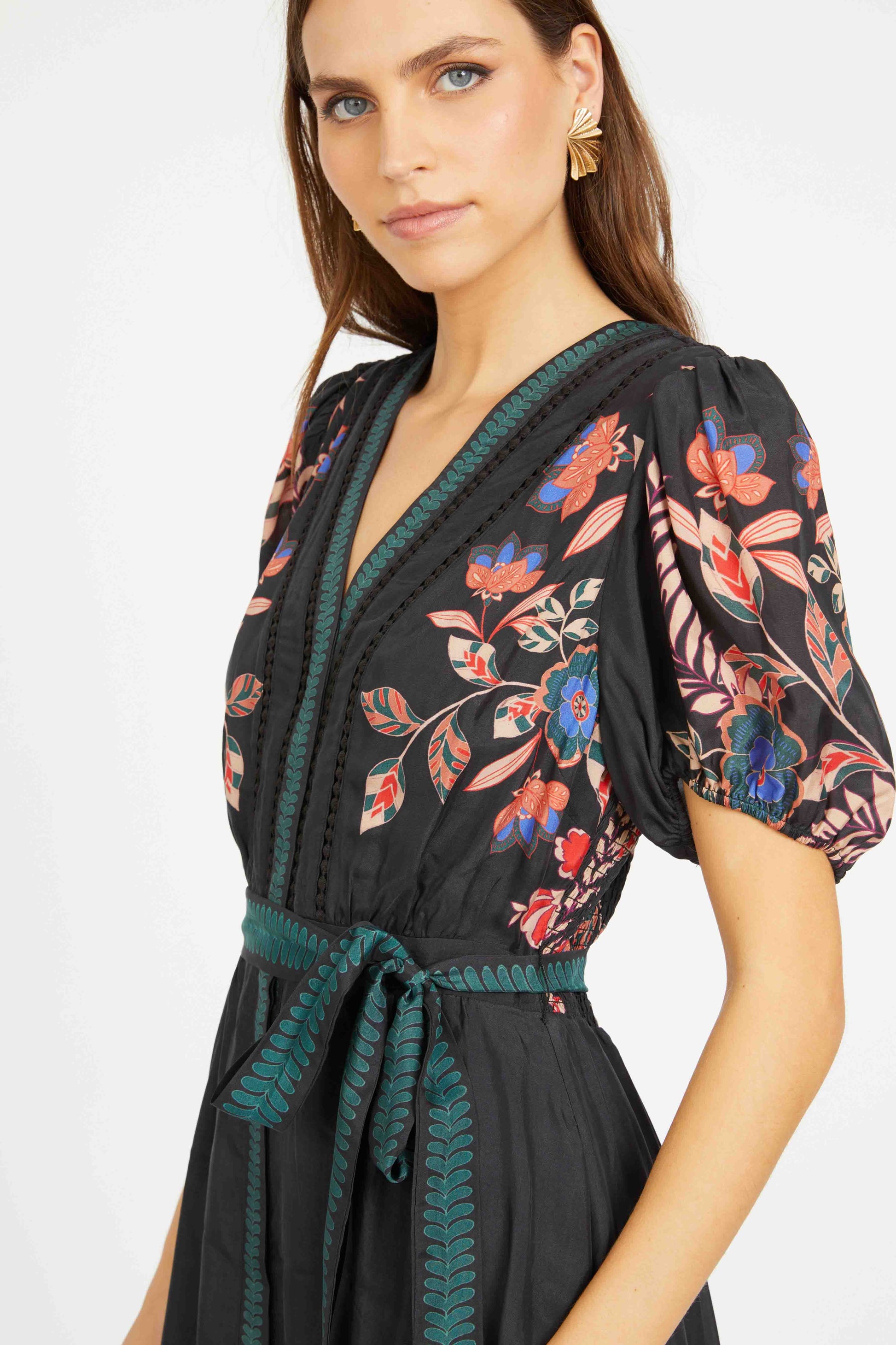 Woman wearing a black floral dress with green accents on a white background