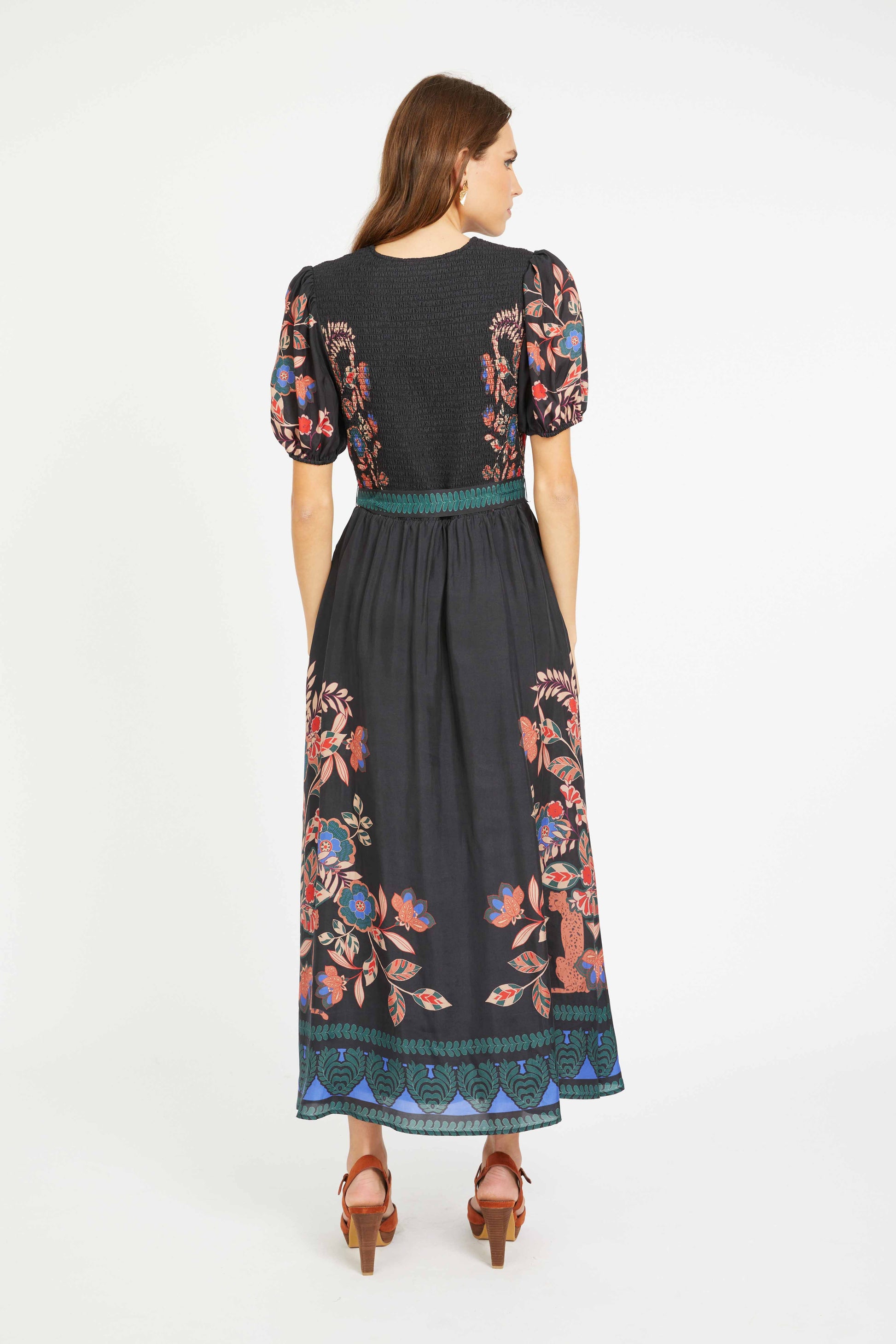 Woman wearing a black dress with colorful floral embroidery on a white background