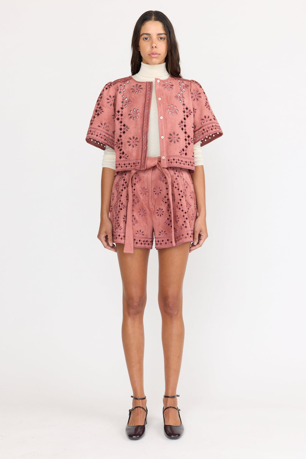 Woman wearing a pink embroidered outfit on a white background