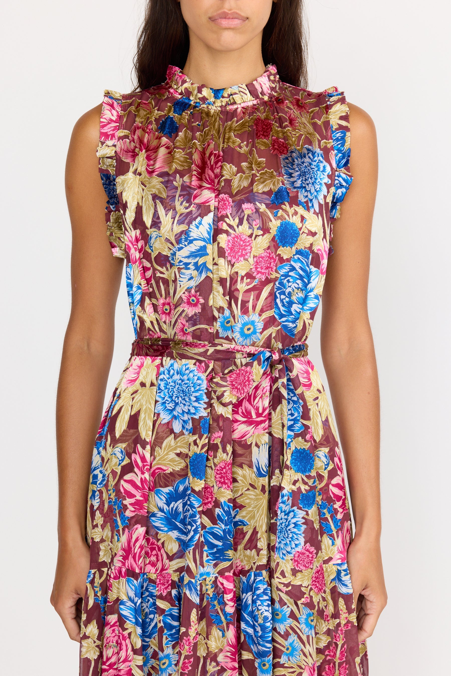 Woman wearing a sleeveless floral dress with a colorful pattern on a white background