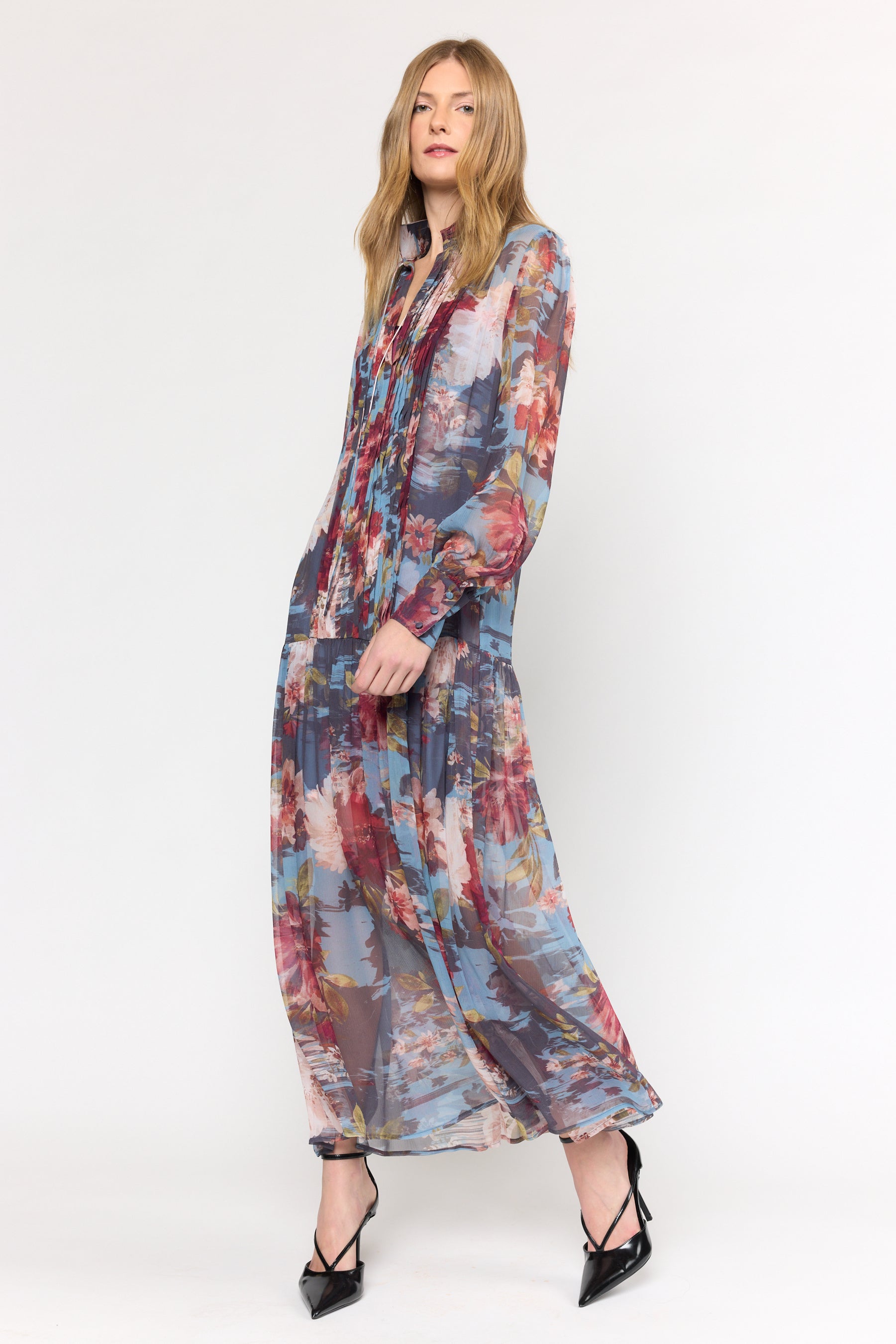 Woman wearing a long, multicolored floral dress on a white background